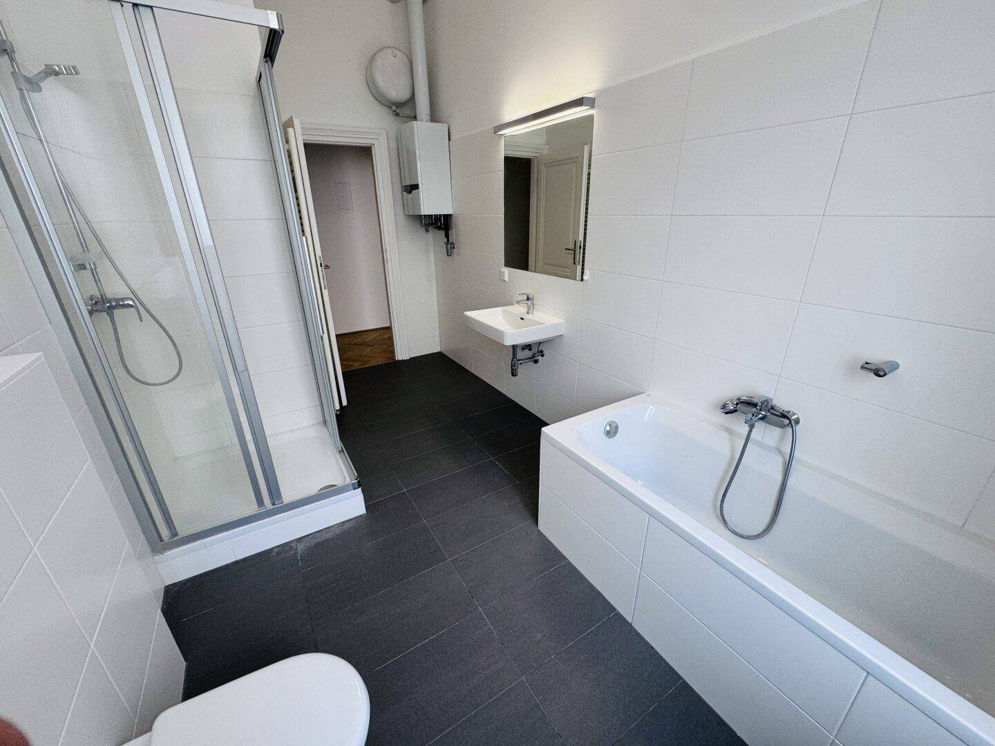 Helles Badezimmer mit Duschkabine, Badewanne und modernem Waschtisch.