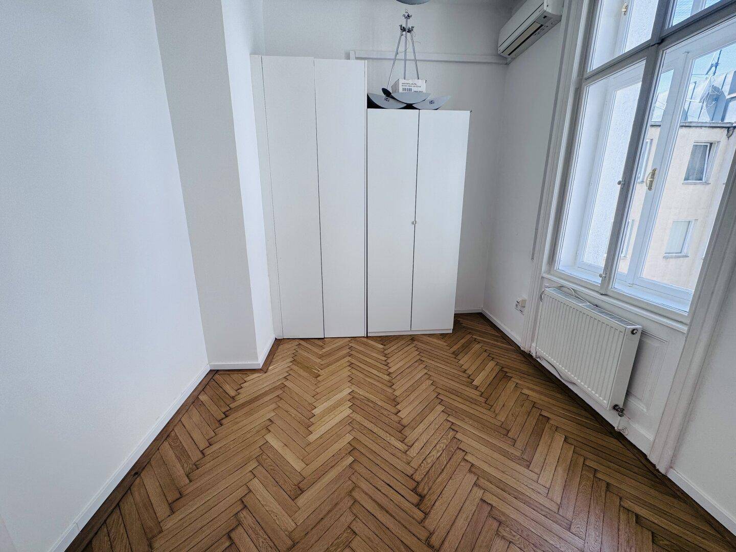 Helles Zimmer mit Fischgrätparkett, Einbauschrank und Klimaanlage, ideal als Schlaf- oder Arbeitszimmer.
