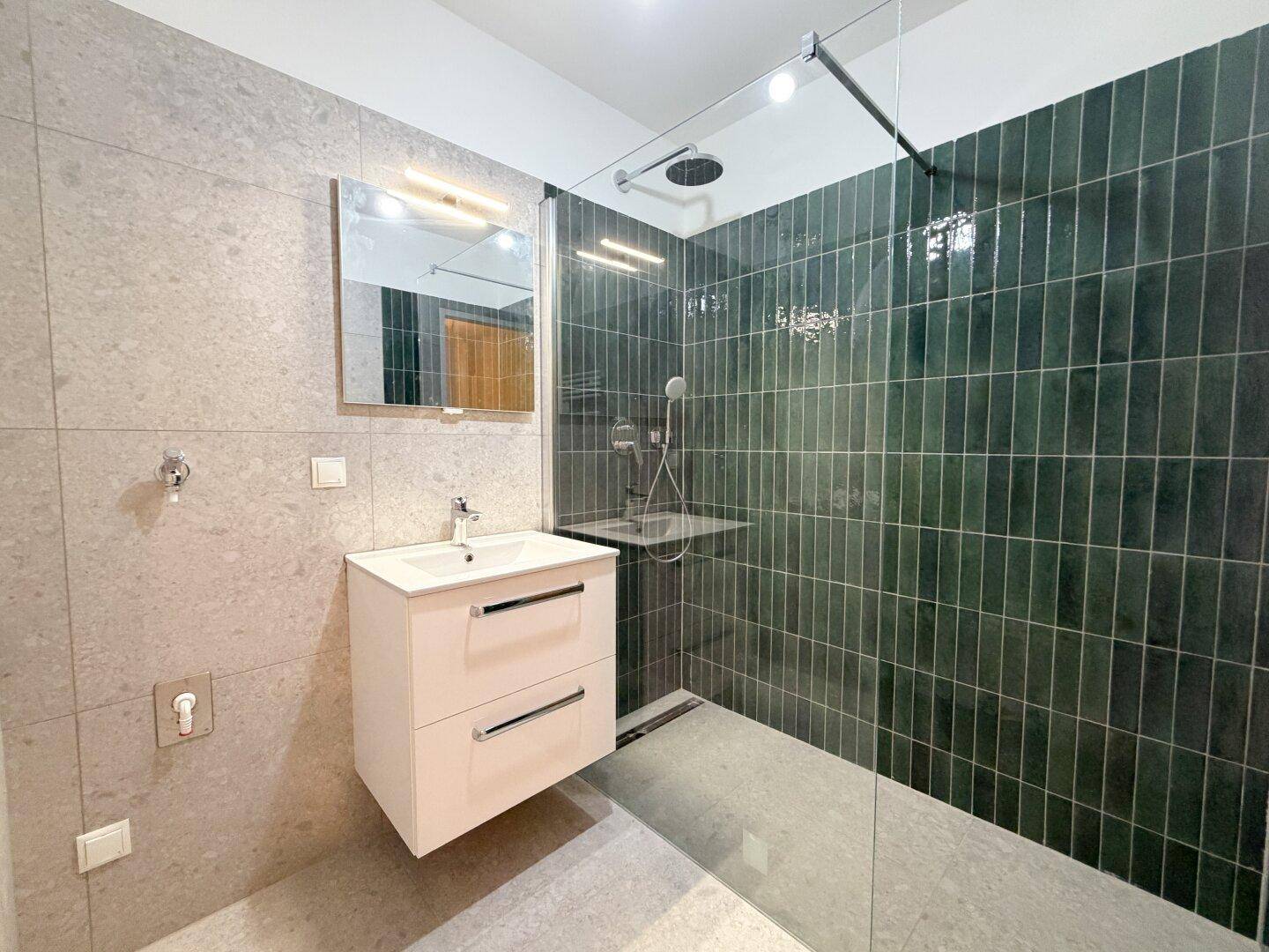 Helles Badezimmer mit moderner begehbarer Dusche, Waschtisch und eleganten grauen Fliesen.