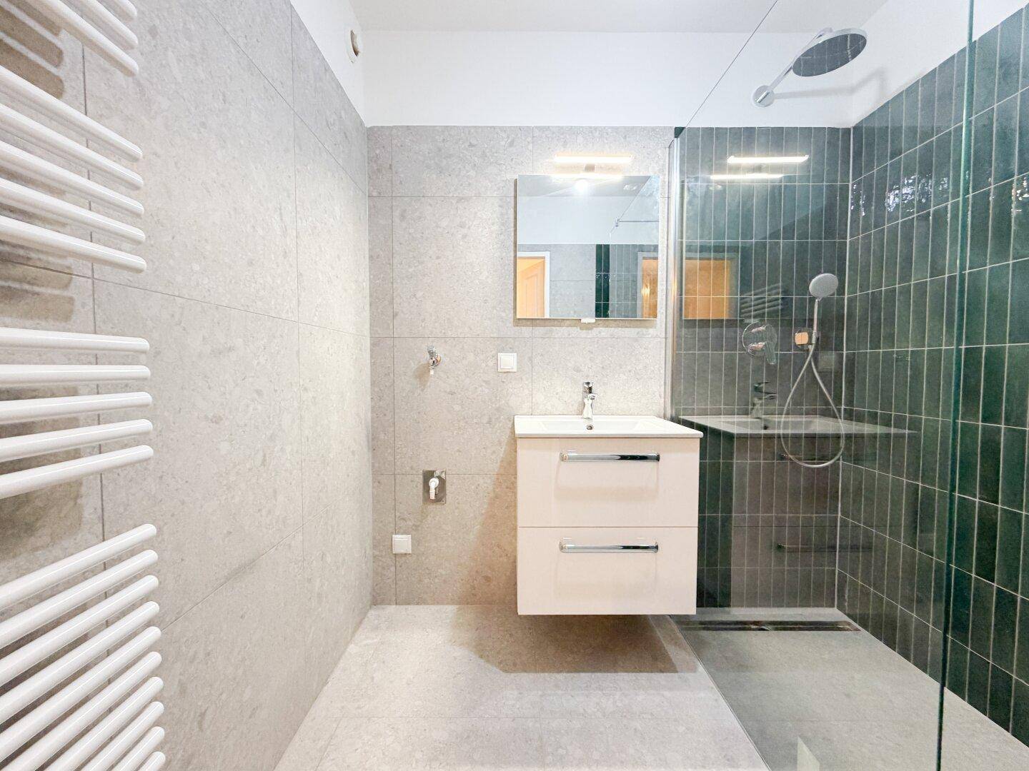 Modernes Badezimmer mit begehbarer Dusche, schwebendem Waschtisch und beheiztem Handtuchhalter.