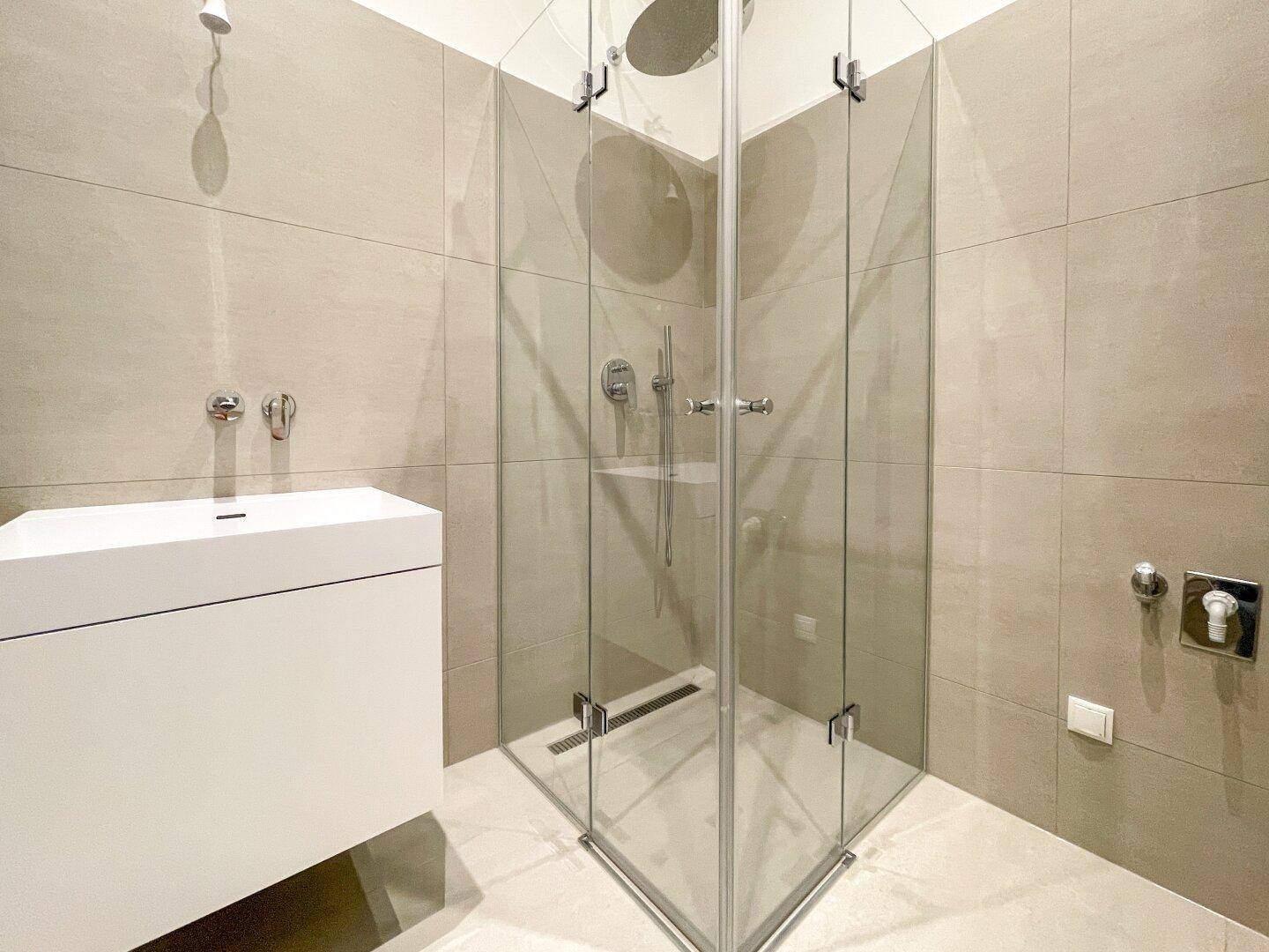 Elegantes Badezimmer mit Eckduschkabine, Regendusche und modernem Waschtisch.