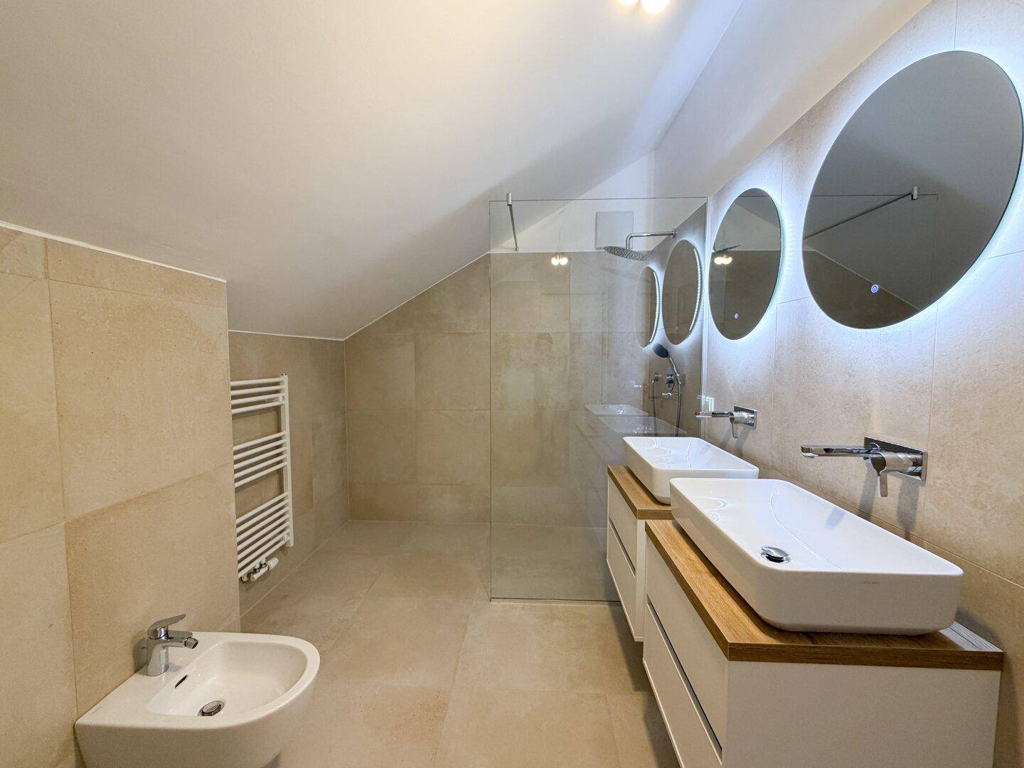 Modernes Badezimmer mit Doppelwaschbecken, begehbarer Dusche, Bidet und beheiztem Handtuchhalter.
