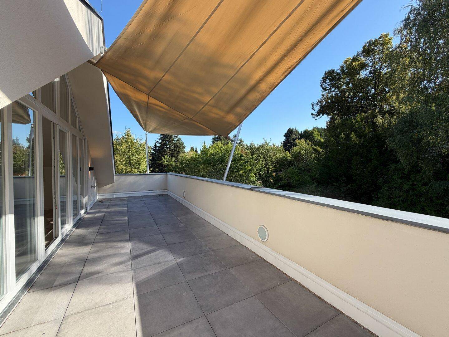 Weitläufige Terrasse mit moderner Markise und Zugang zu den Innenräumen.