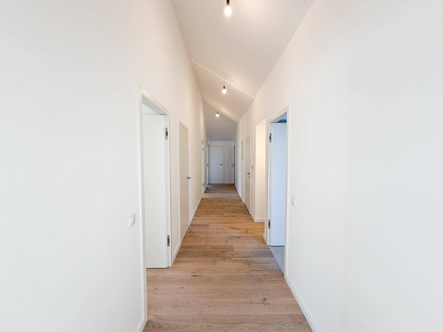Heller Flur mit Holzboden und mehreren Türen, der zu verschiedenen Räumen führt.