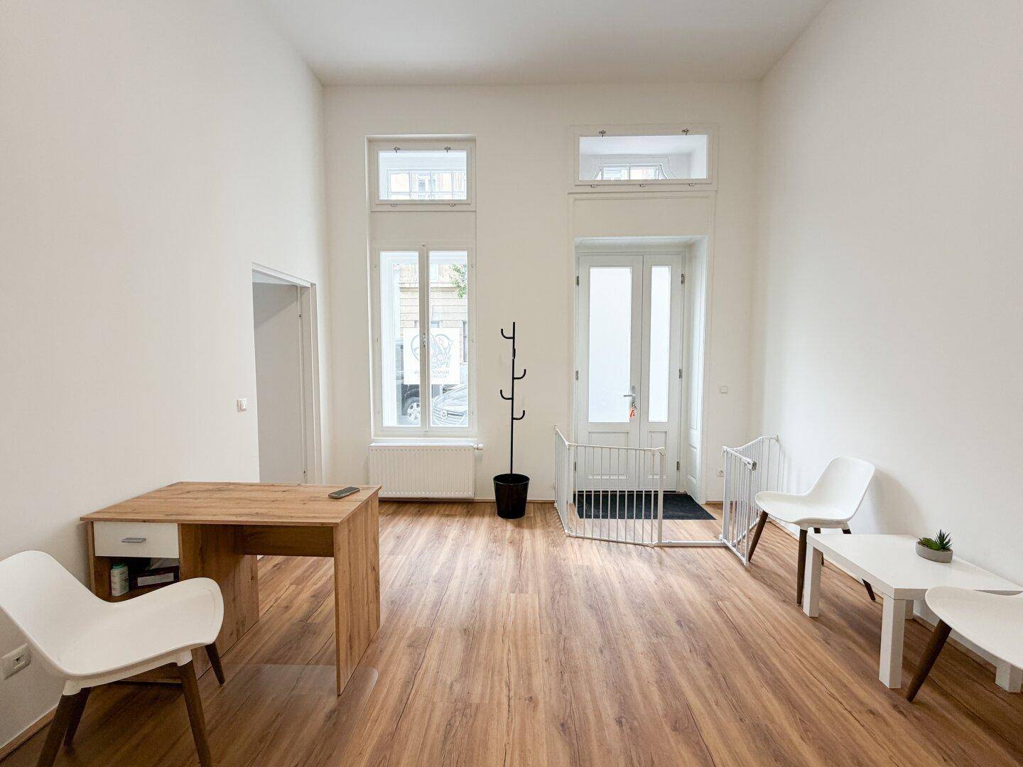 Heller, möblierter Geschäftsraum mit Holzboden, Schreibtisch und Sitzgelegenheiten, bereit zur Nutzung.