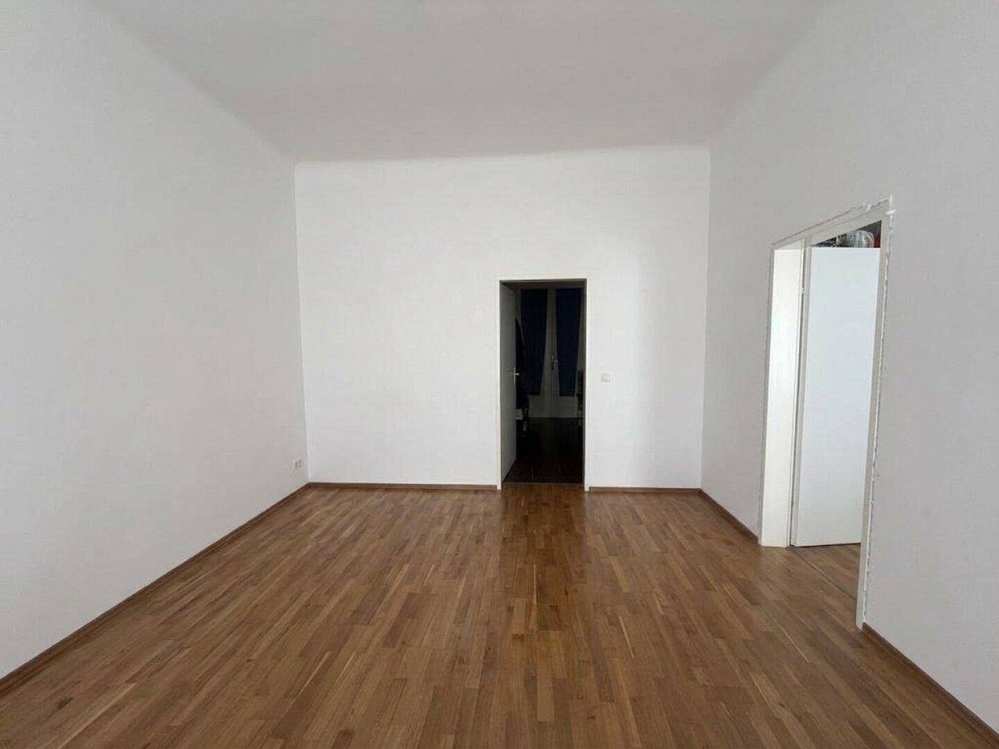Geräumiges, leeres Zimmer mit Holzboden und weiß gestrichenen Wänden, ideal für individuelle Gestaltung.