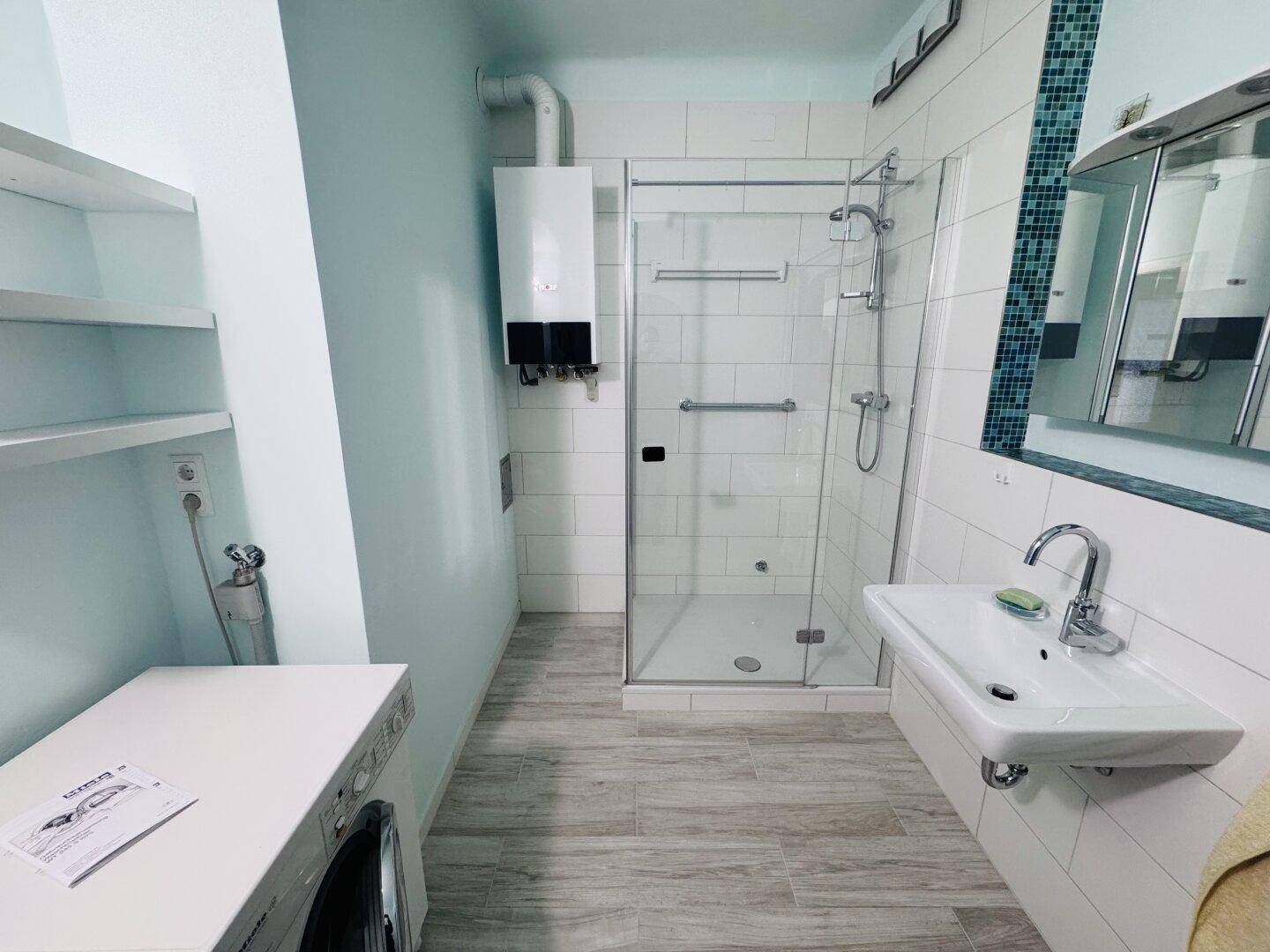 Modernisiertes Badezimmer mit Dusche, Waschbecken und Gastherme.