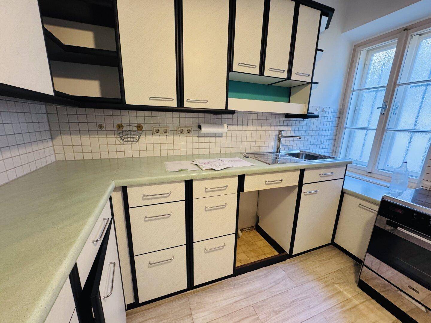 Detailansicht der Küche mit Spülbecken, Arbeitsplatte und Fenster.