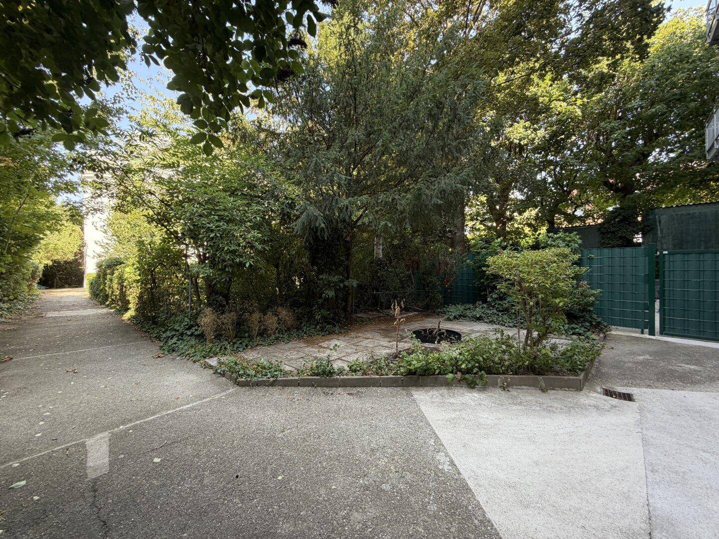 Grüne Gartenanlage mit Bäumen und Sträuchern, die eine ruhige Atmosphäre schafft.