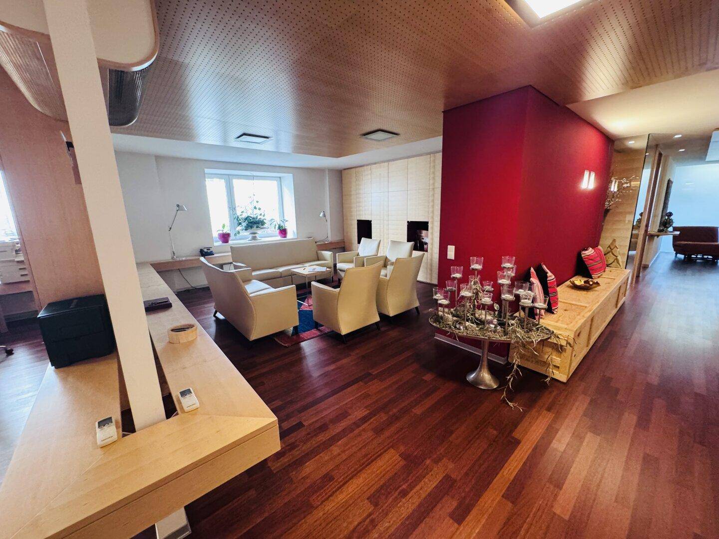 Wartebereich oder Lounge in einem Büro mit bequemen Sofas, Sesseln und einem roten Akzentwand.