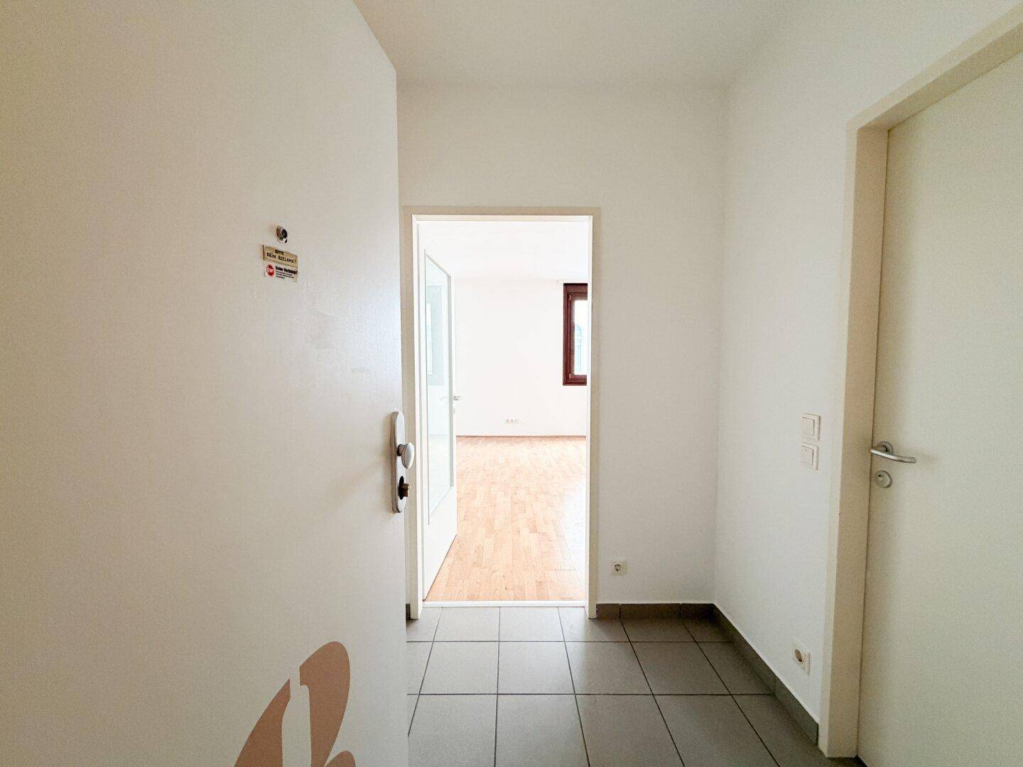Heller Eingangsbereich mit Fliesenboden und offener Tür zu den Wohnräumen.