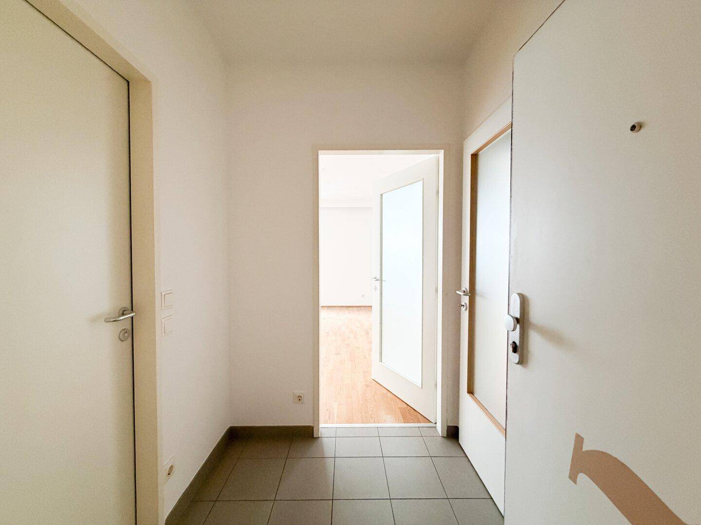 Heller Eingangsbereich mit Fliesenboden und mehreren Türen, die zu den Wohnräumen führen.