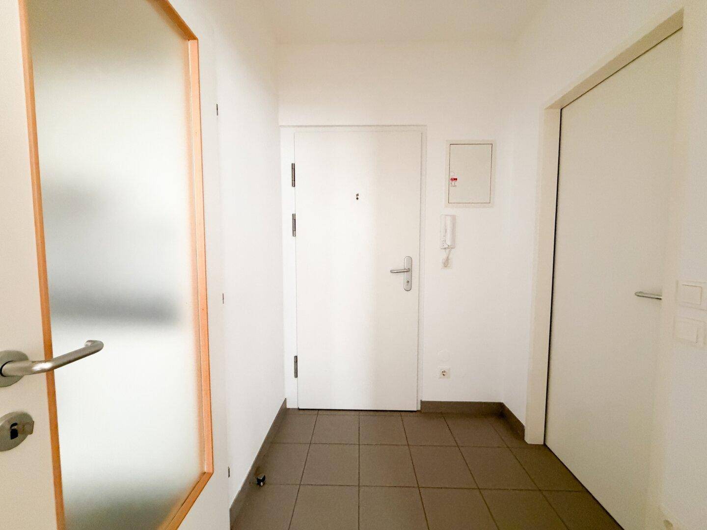 Eingangsbereich mit Fliesenboden, Gegensprechanlage und Zugang zu den verschiedenen Zimmern.