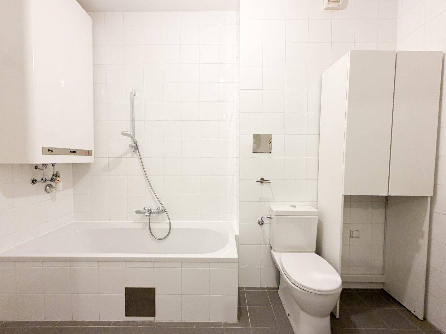 Badezimmer mit Badewanne, Toilette und praktischem Stauraum.
