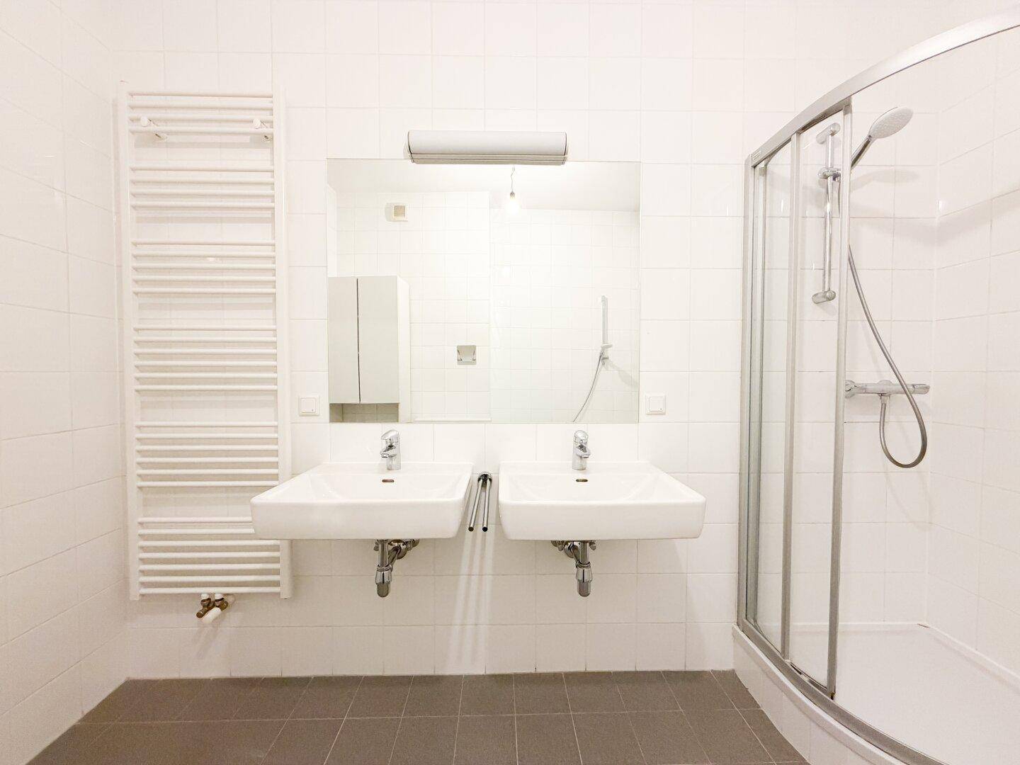 Modernes Badezimmer mit Doppelwaschbecken, großem Spiegel und Handtuchheizkörper.