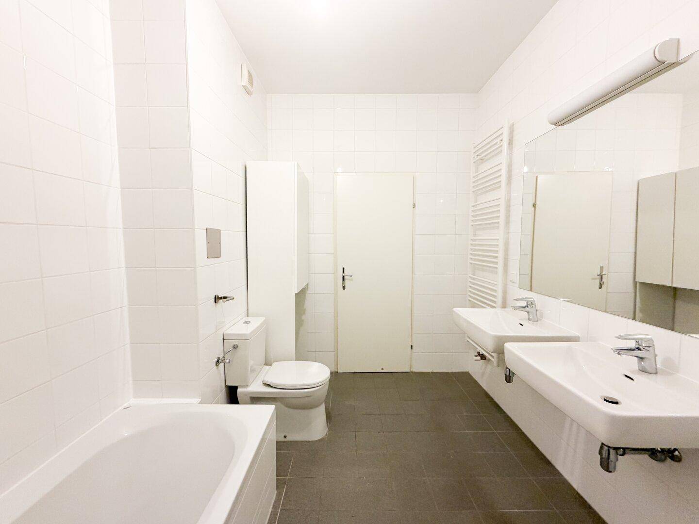 Geräumiges Badezimmer mit Badewanne, Toilette und Doppelwaschbecken.