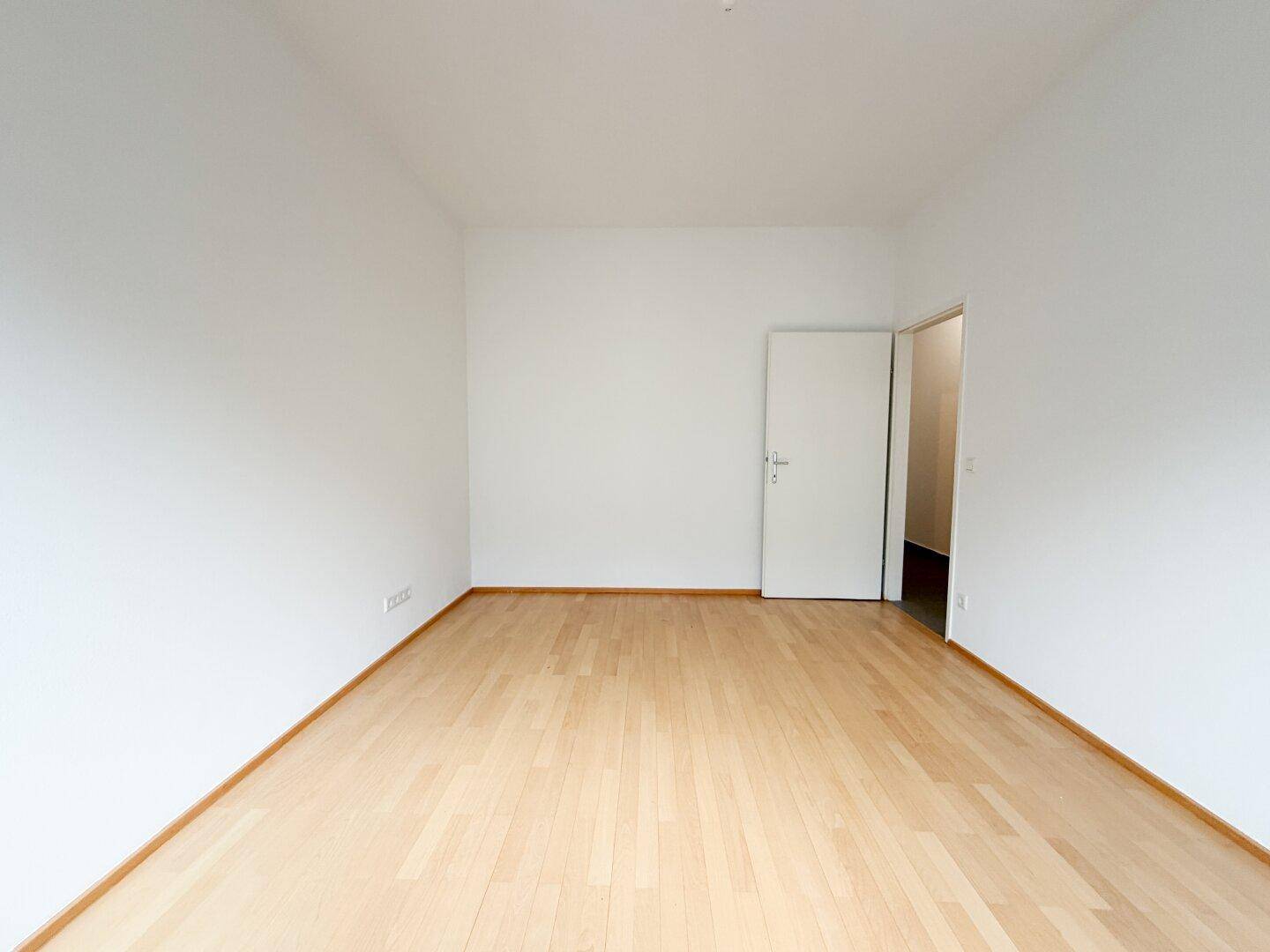 Leeres Schlafzimmer mit hellem Parkettboden und weißen Wänden, bereit zur Einrichtung.