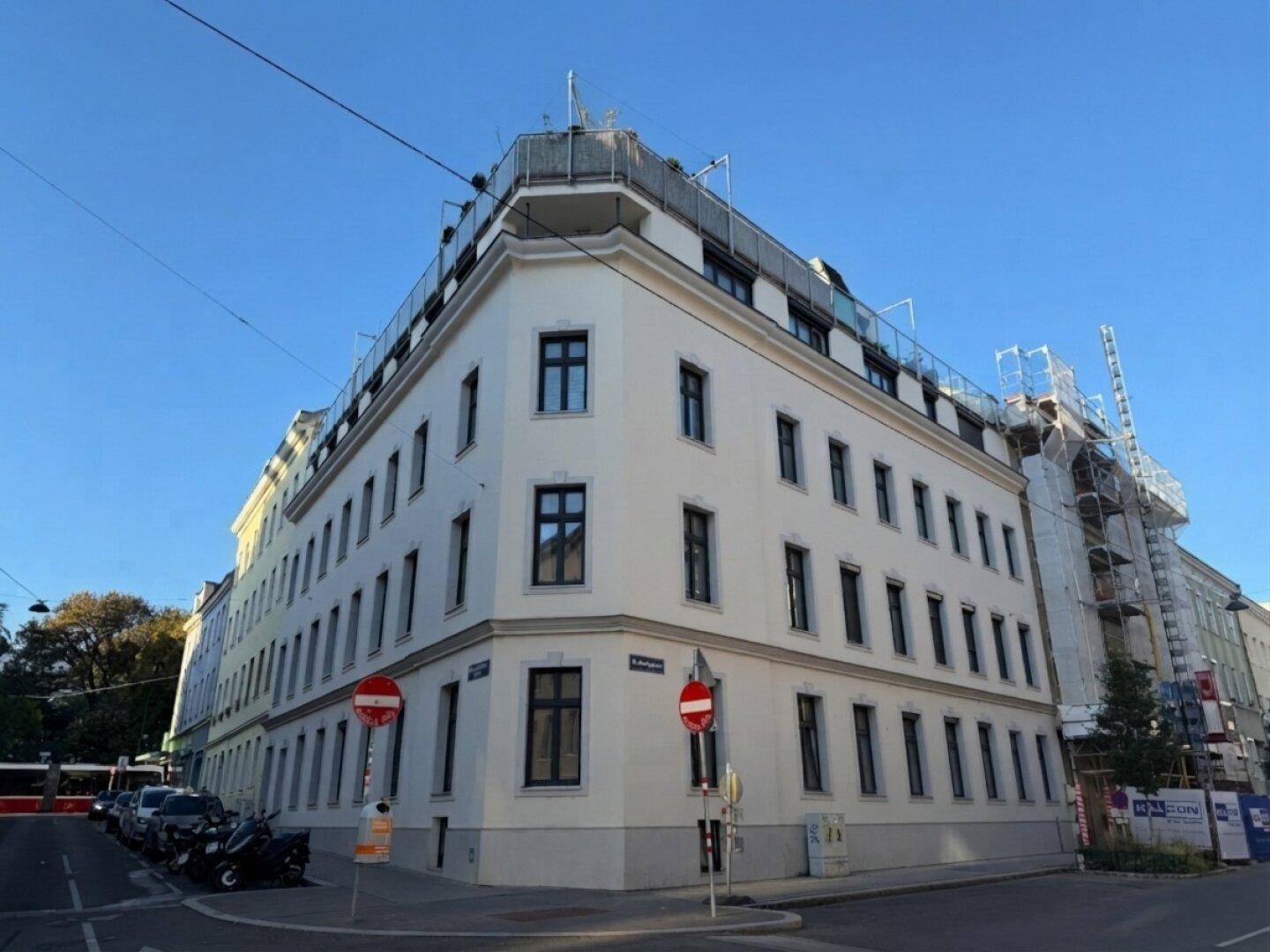 Eckgebäude mit klassischer Architektur und mehreren Etagen an einer städtischen Straße.