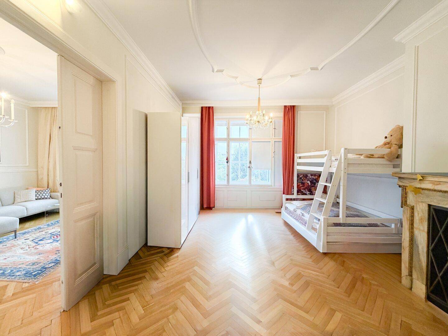 Kinderzimmer mit Etagenbett, dekorativem Kamin und elegantem Fischgrätparkett.