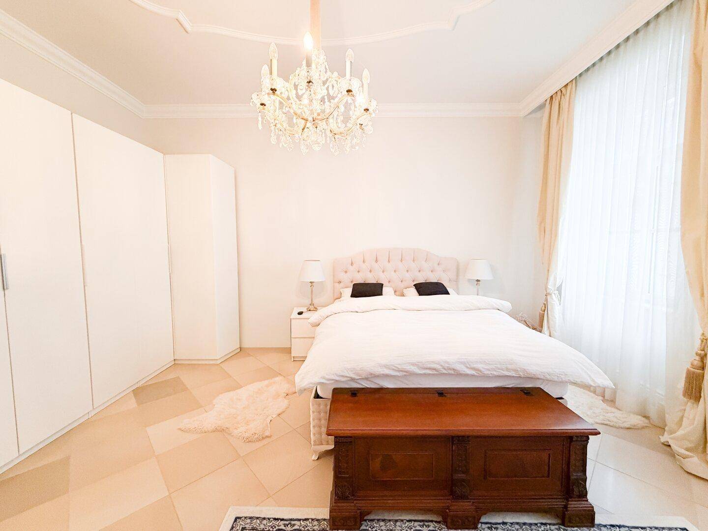 Geräumiges Schlafzimmer mit großem Bett, weißen Schränken und einem antiken Holztruhe.