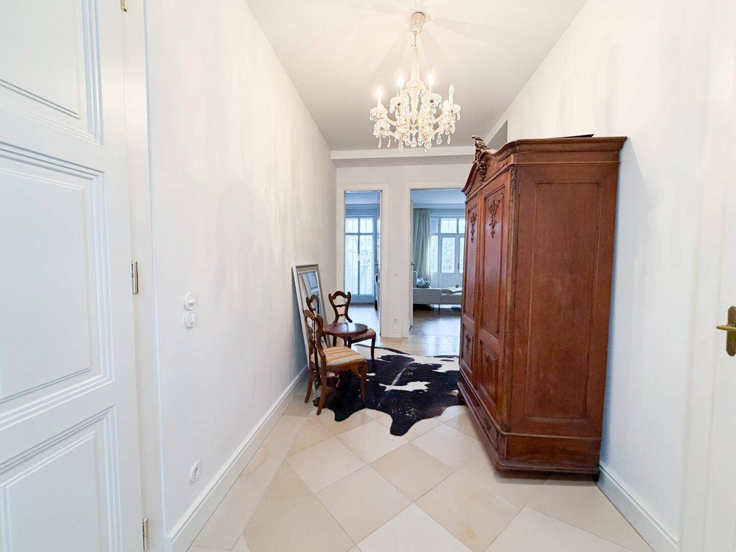 Geräumiger Flur mit antikem Holzschrank, Spiegel und Blick in angrenzende Räume.