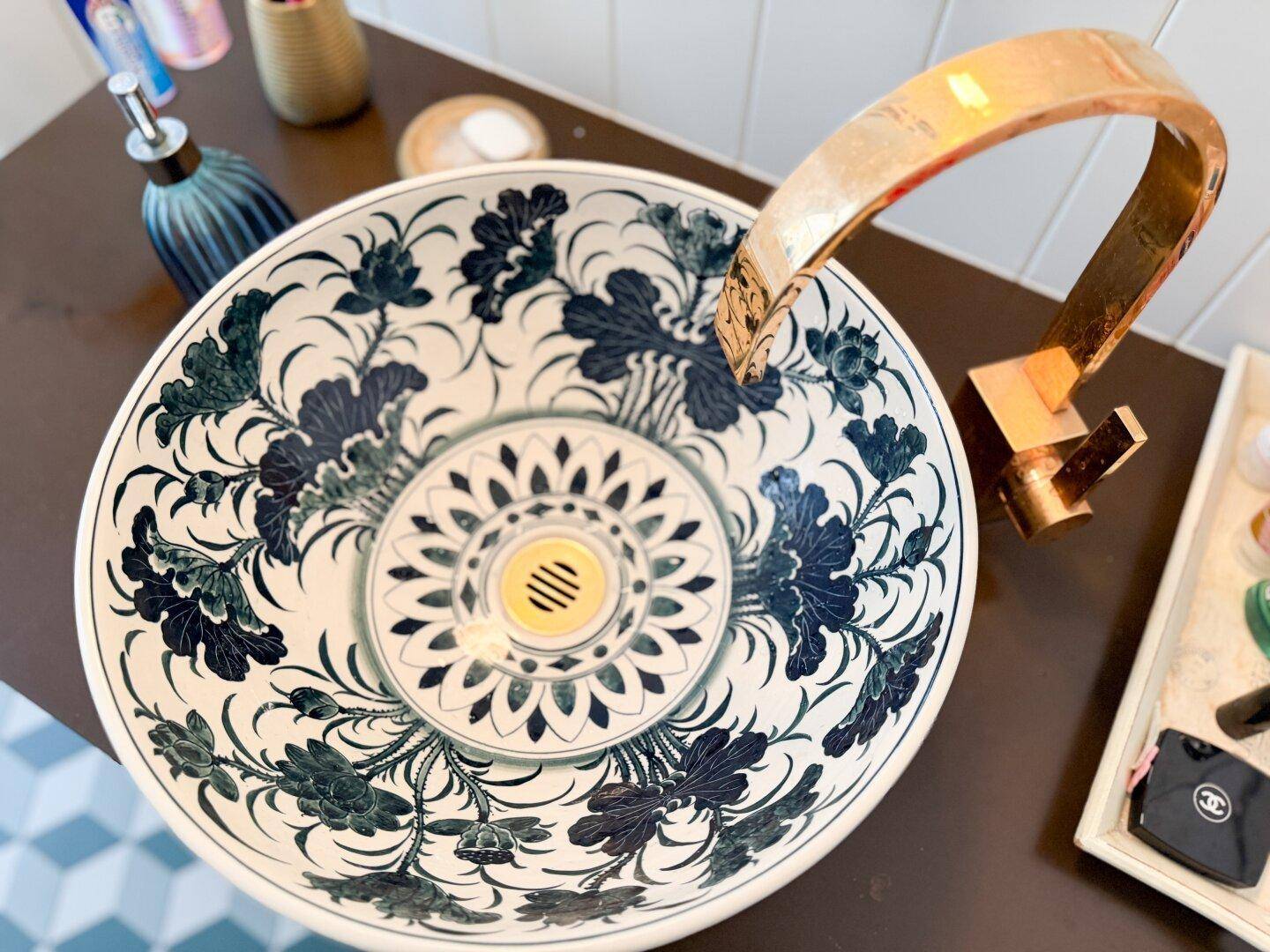 Detailaufnahme eines kunstvoll verzierten Waschbeckens mit einem eleganten goldenen Wasserhahn.