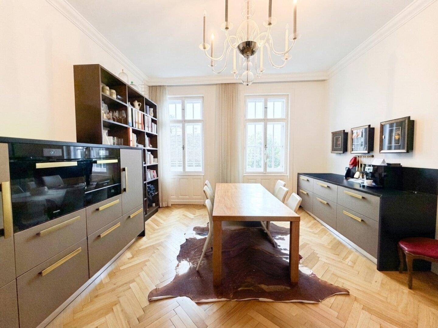 Eleganter Essbereich mit Holztisch, modernen Einbauschränken und klassischem Fischgrätparkett.