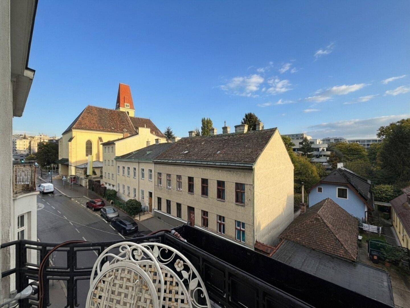 Balkon mit Blick auf die Stadt, historische Gebäude und eine Kirche unter blauem Himmel.