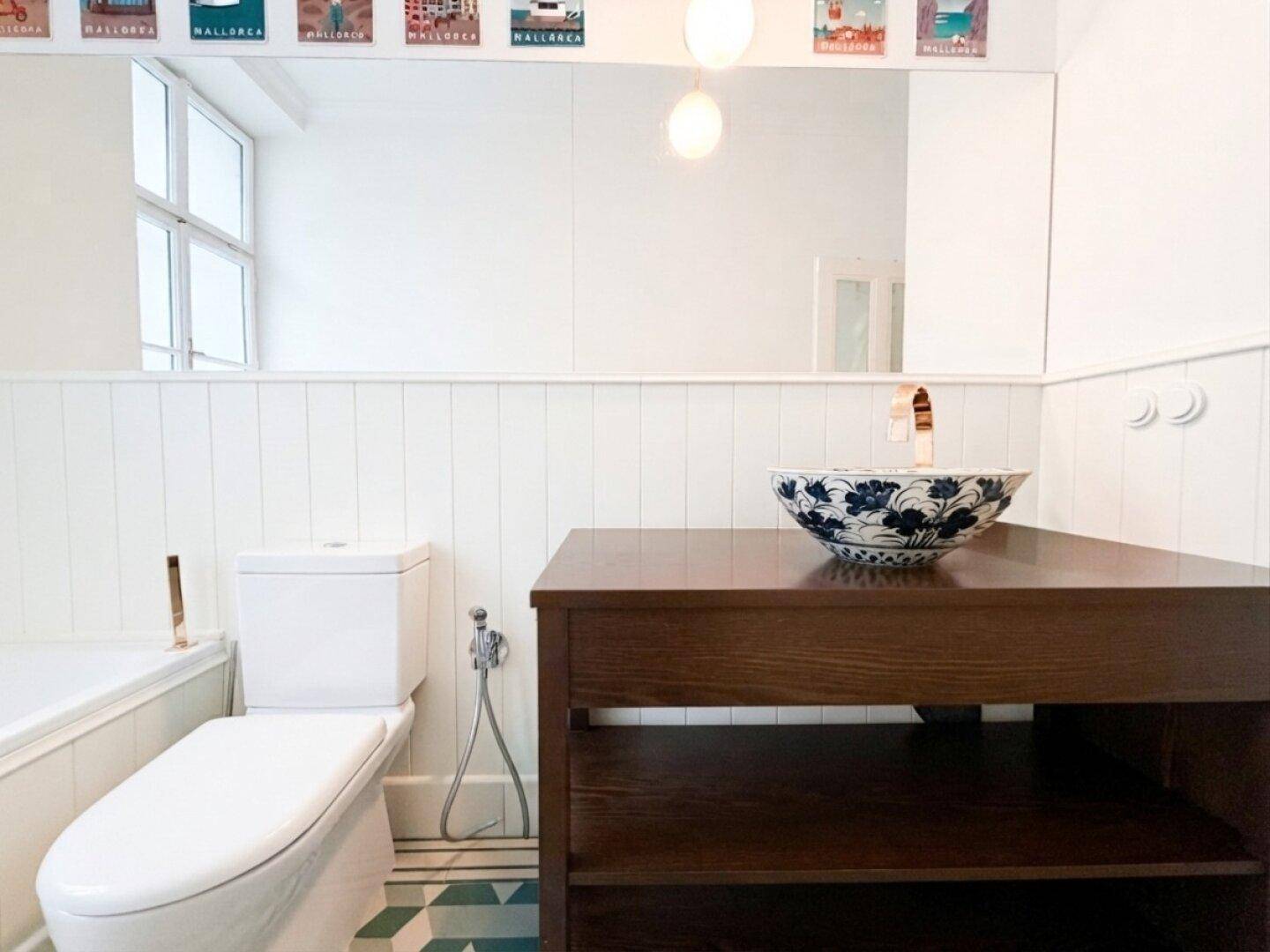 Modernes Badezimmer mit einzigartigem Waschbecken, Toilette und geometrischen Bodenfliesen.