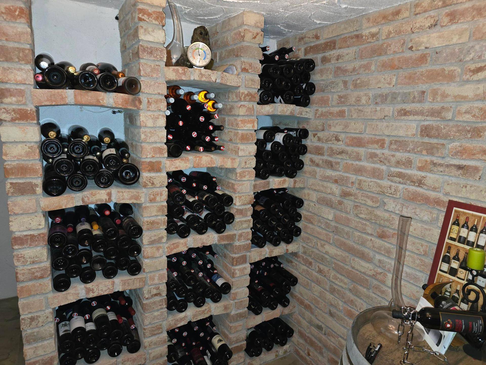 Rustikaler Weinkeller mit Ziegelwänden und zahlreichen Weinregalen.