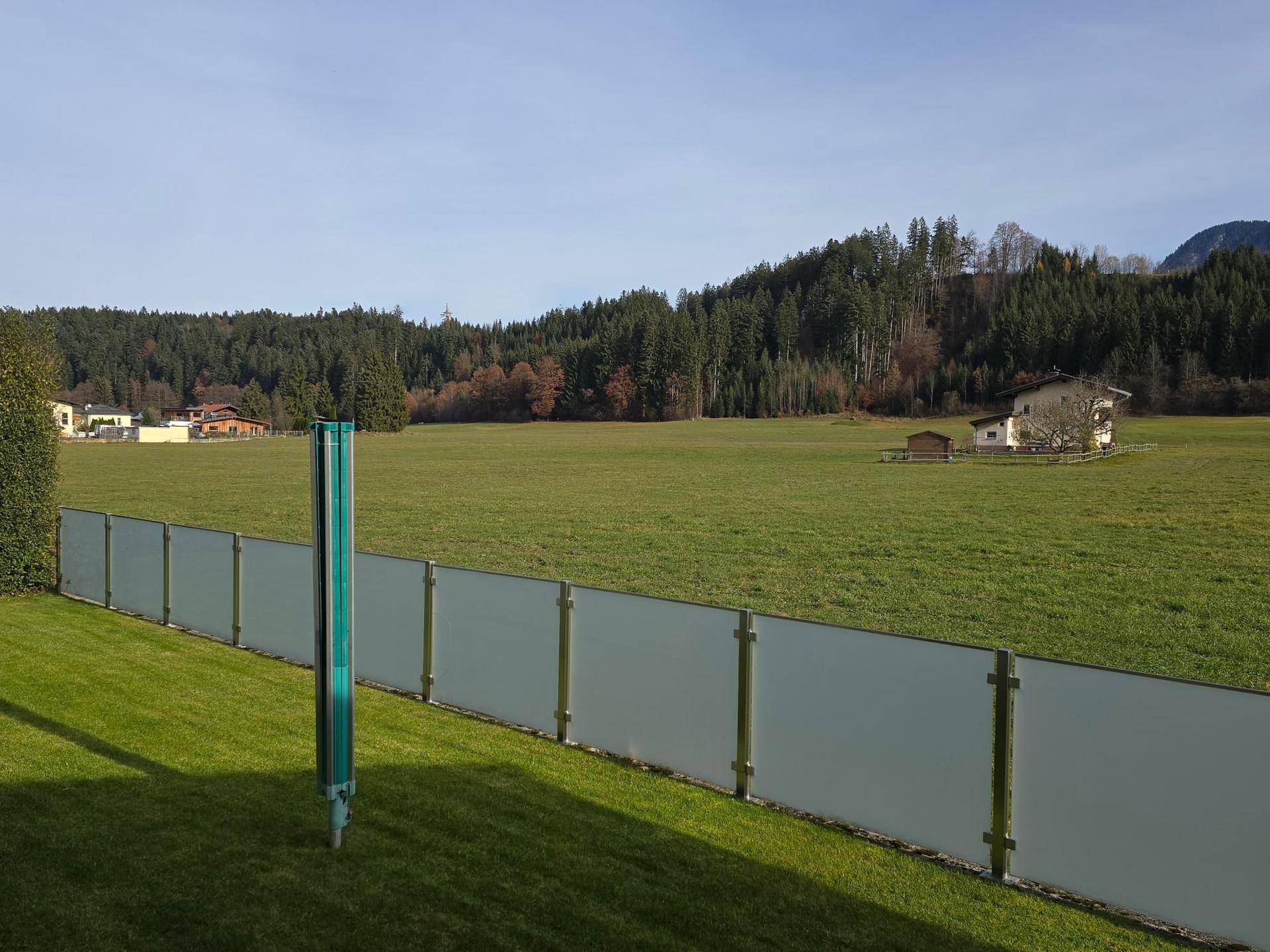 Weitläufige grüne Landschaft mit Waldrand und Blick auf die umliegende Natur.