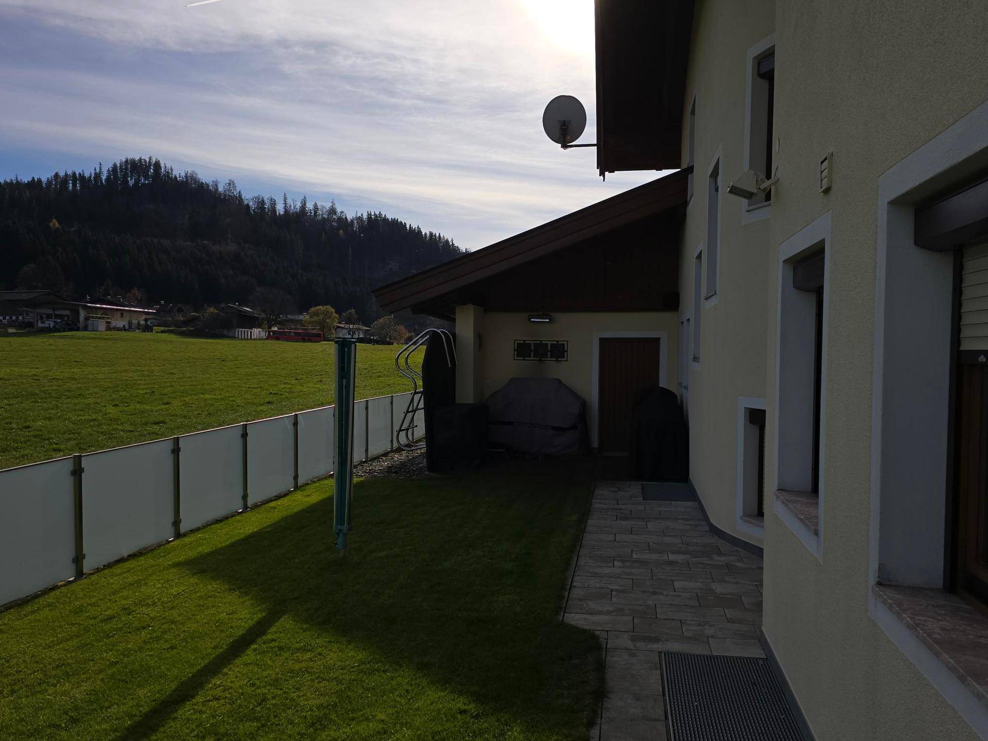 Gartenbereich neben dem Haus mit Rasenfläche, Steinweg und Blick auf die umliegende Landschaft.