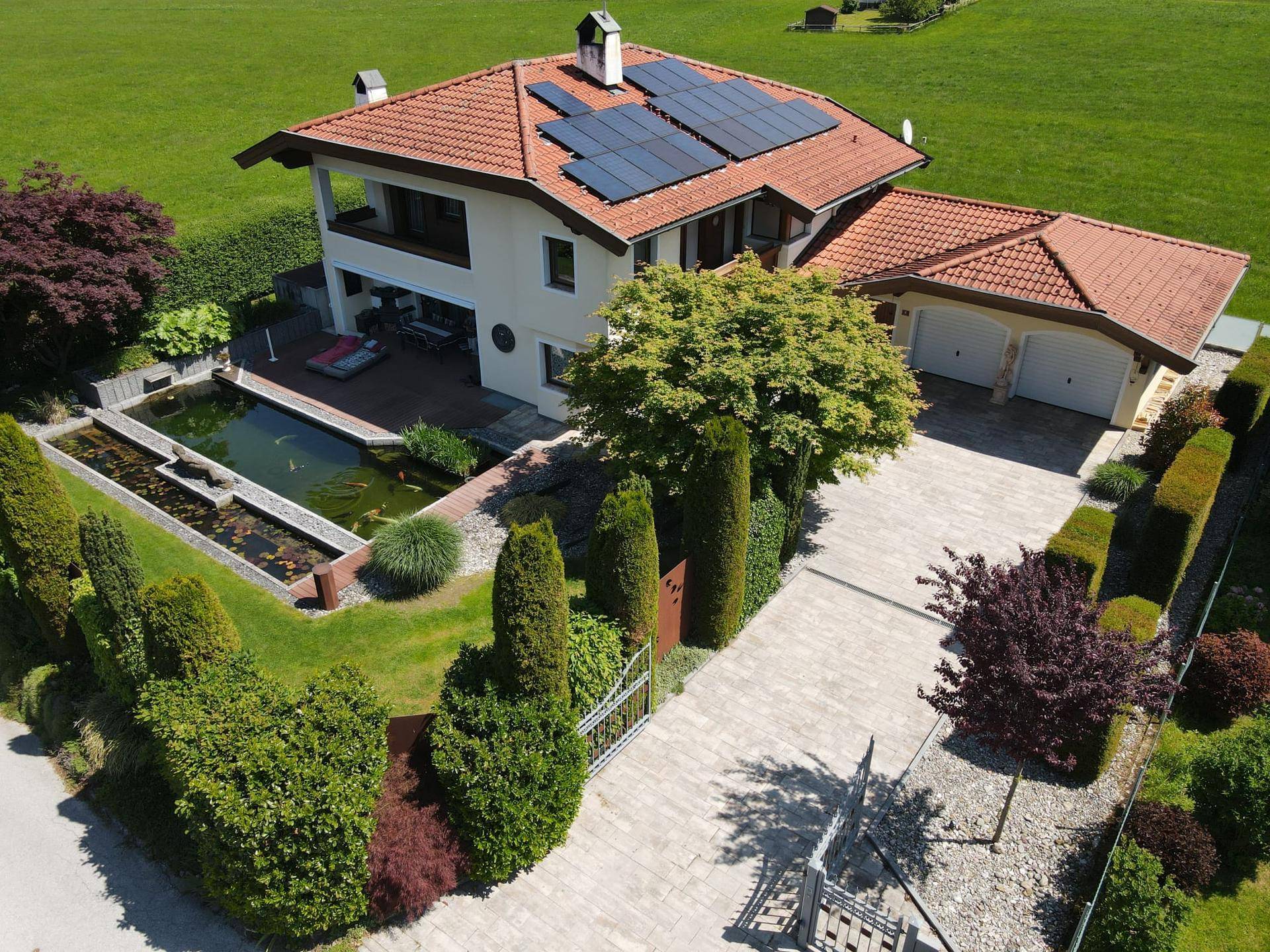 Übersicht des Anwesens aus der Luft mit Garten, Teich, Doppelgarage und weitläufiger Zufahrt.