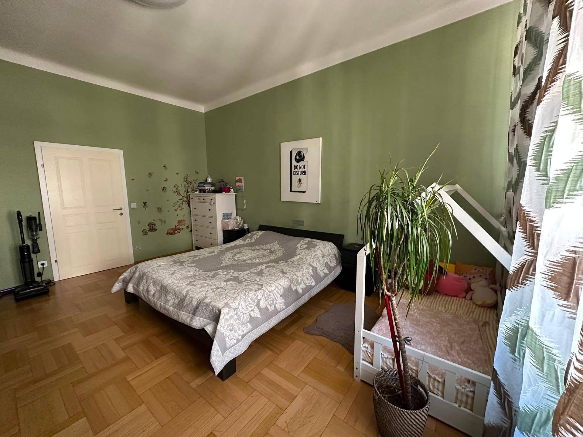 Gemütliches Schlafzimmer mit Parkettboden, grünen Wänden und großem Kleiderschrank.