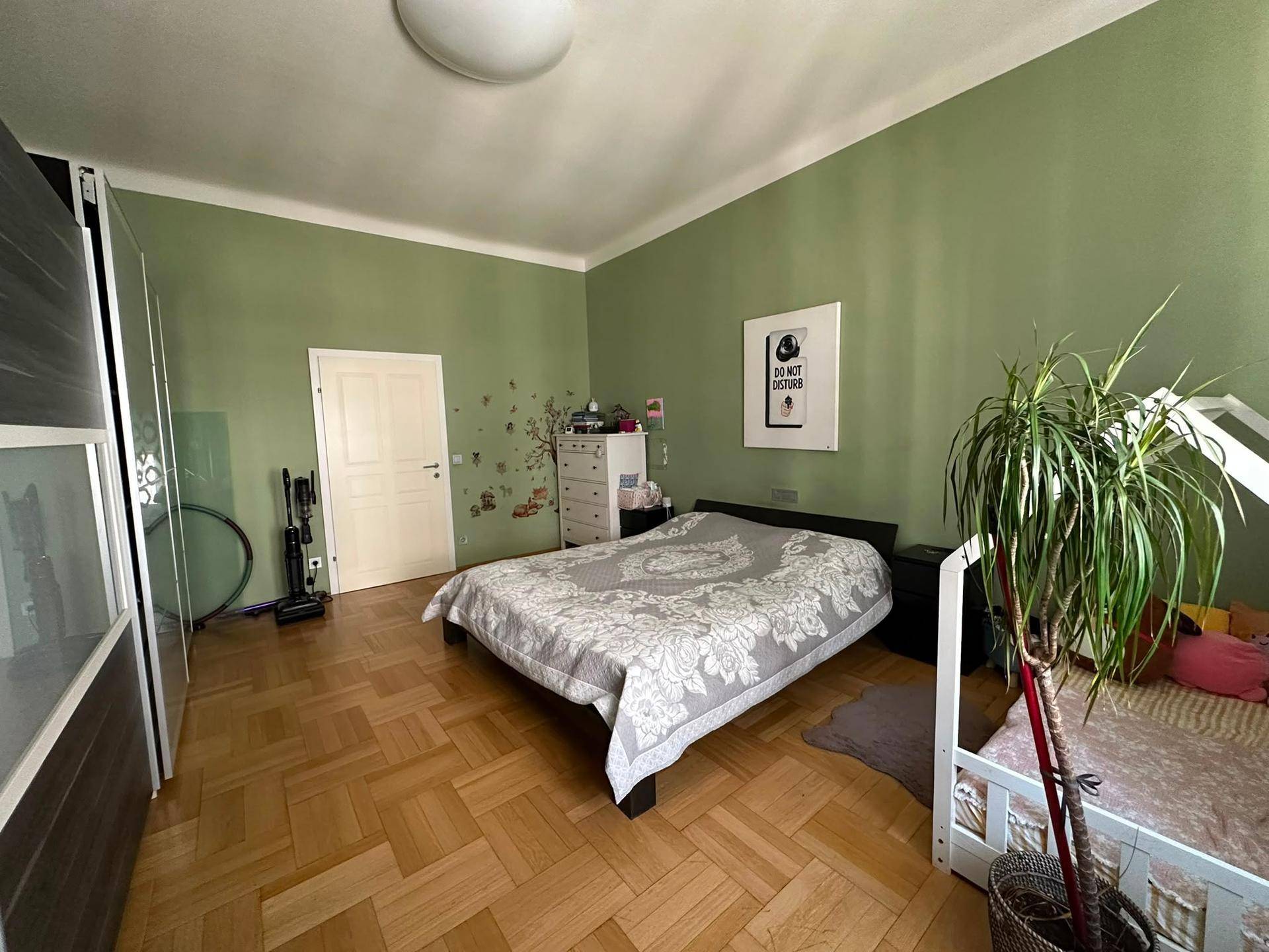 Geräumiges Schlafzimmer mit Parkettboden, grünen Wänden und großem Kleiderschrank.