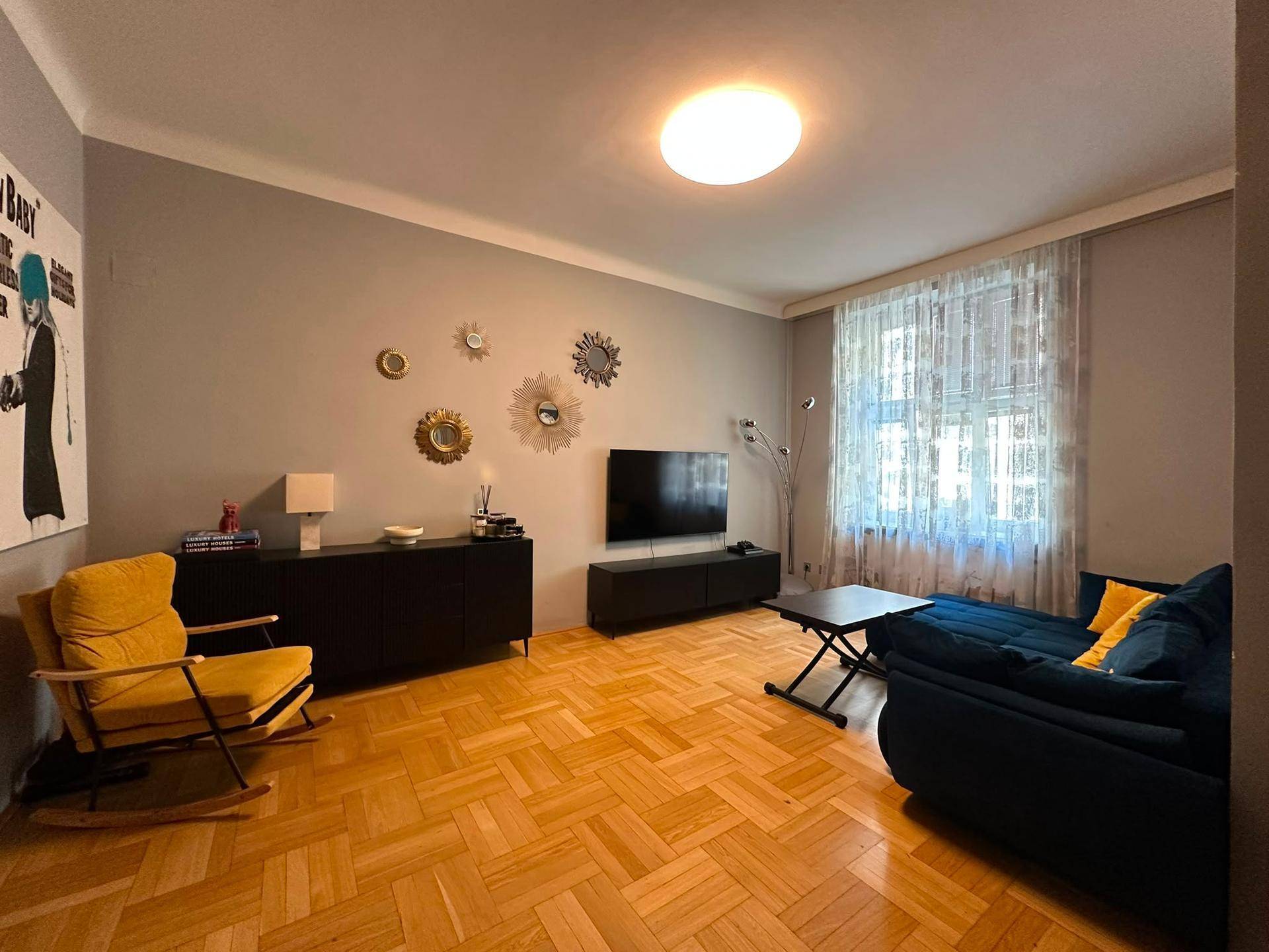 Helles Wohnzimmer mit modernem Sofa, gelbem Sessel und Parkettboden.