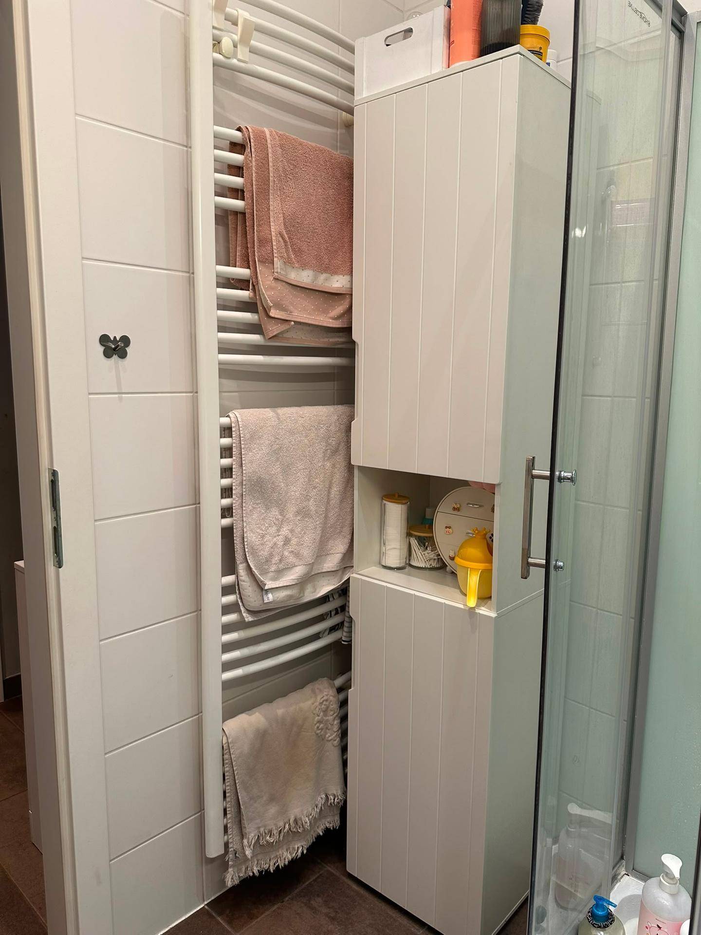 Detailansicht des Badezimmers mit beheiztem Handtuchhalter und praktischem Hochschrank.