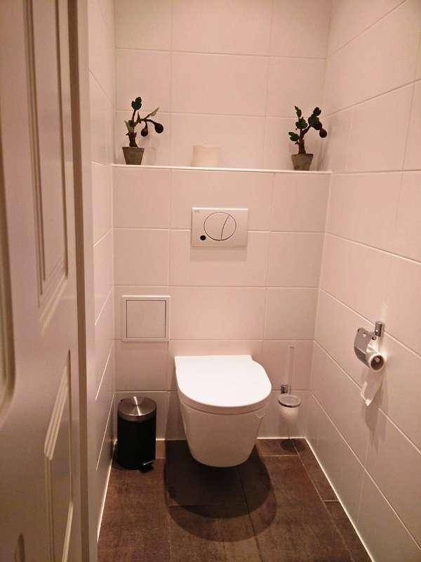 Modernes Gäste-WC mit wandhängender Toilette und weißen Fliesen.