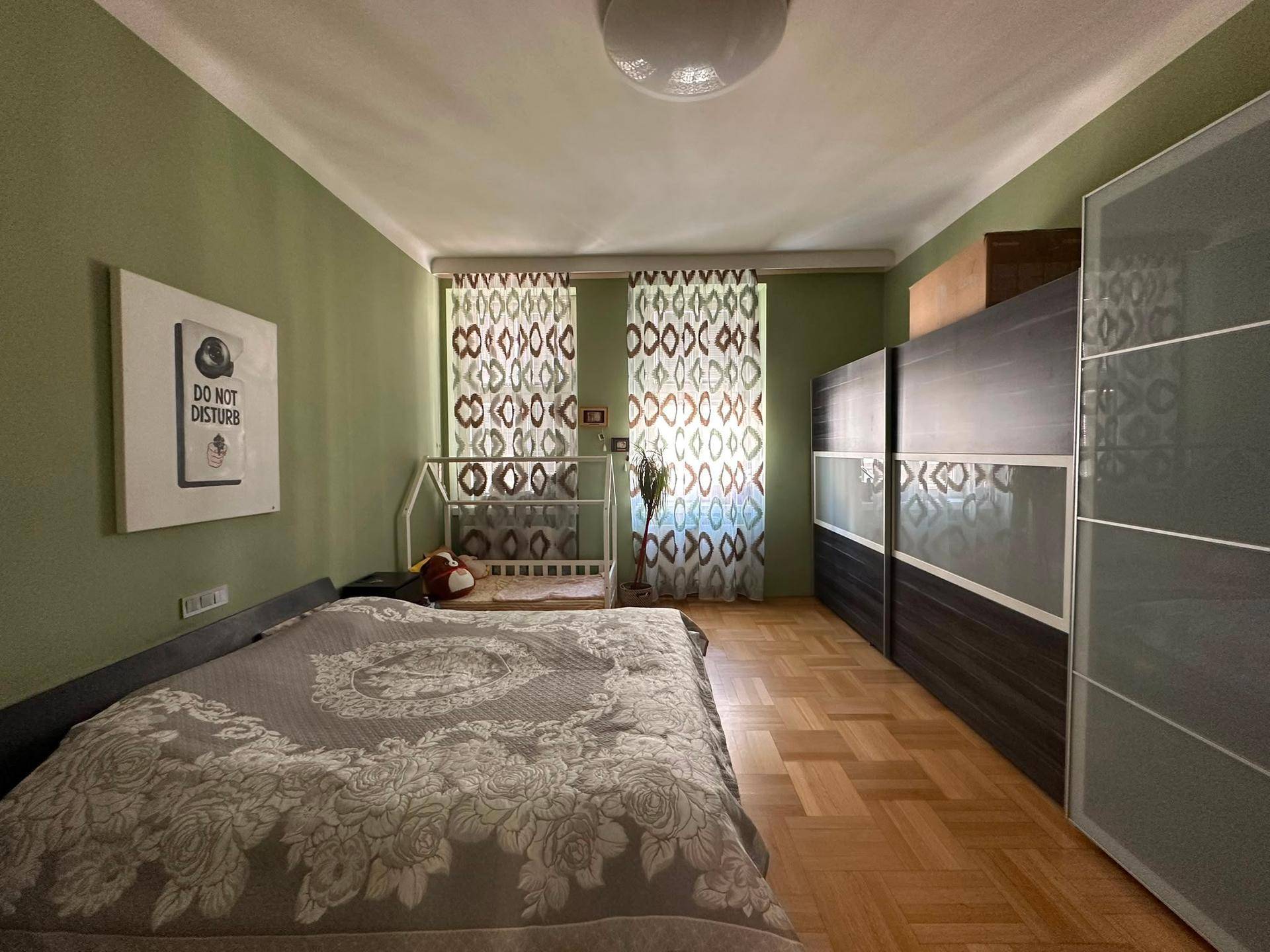 Geräumiges Schlafzimmer mit Parkettboden, grünen Wänden und großem Kleiderschrank.