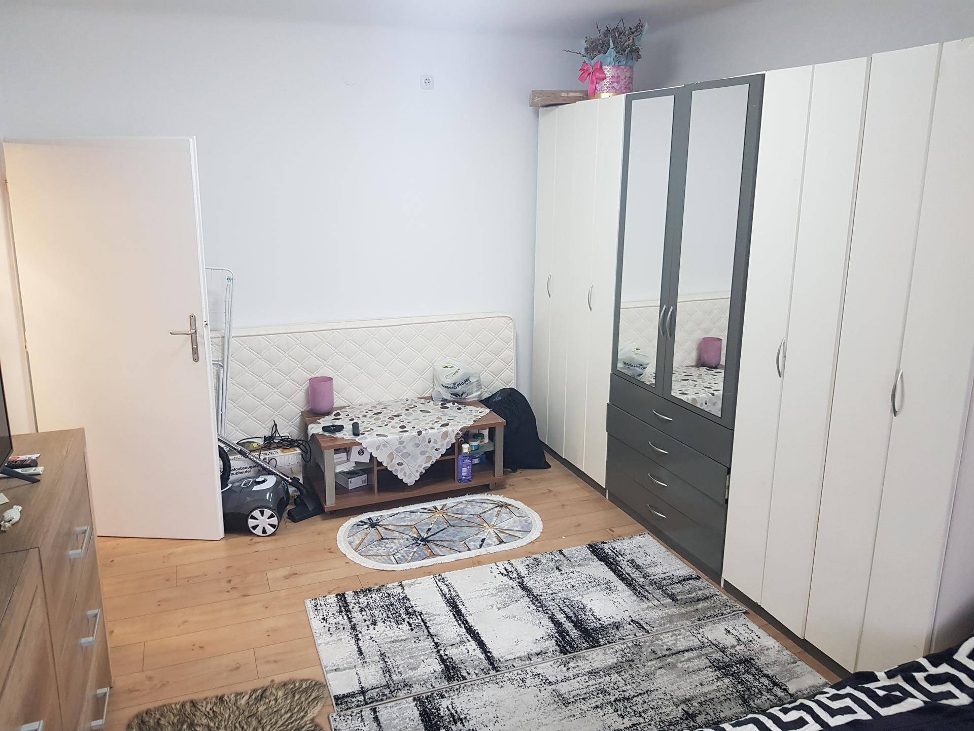 Schlafzimmer mit Bett, großem Kleiderschrank mit Spiegeltüren und Holzboden.
