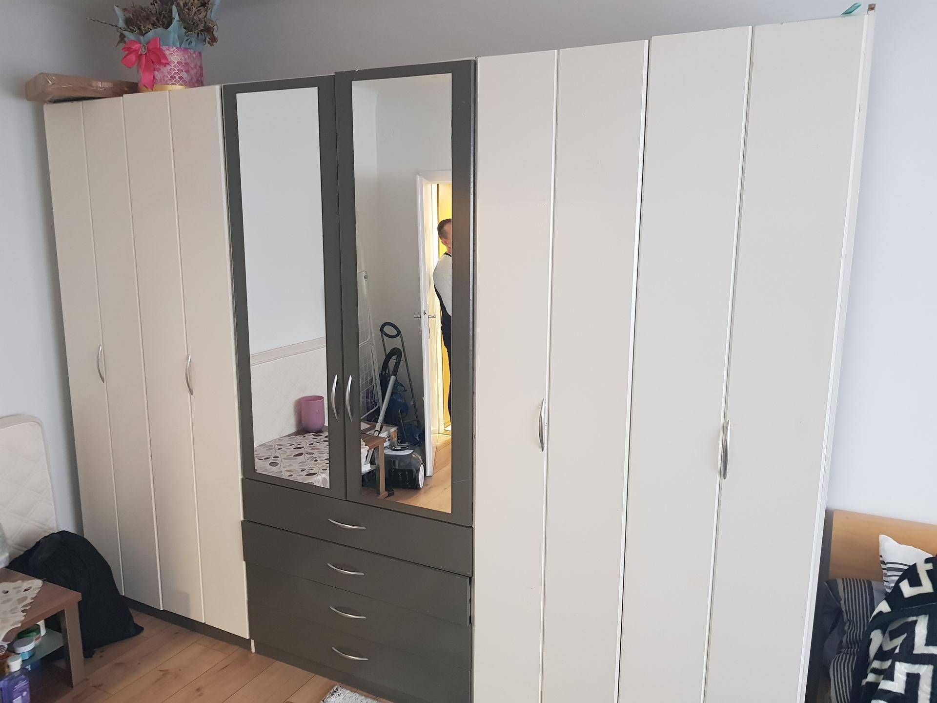 Großer Kleiderschrank mit Spiegeltüren und Schubladen im Schlafzimmer.