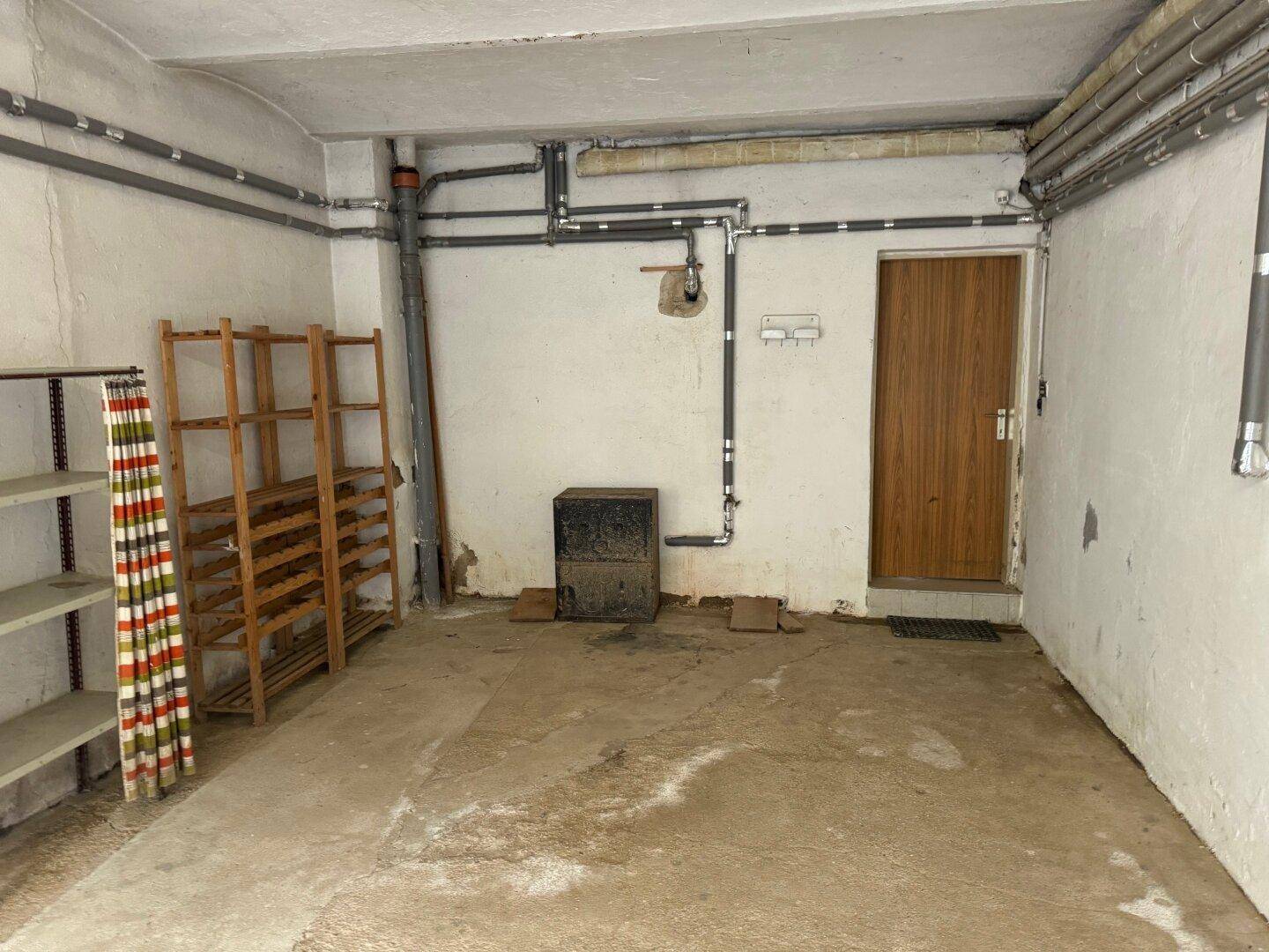 Hinterer Bereich der Garage mit Regalen, Heizungsanlage und einer Holztür, ideal für Werkstatt oder Lager.