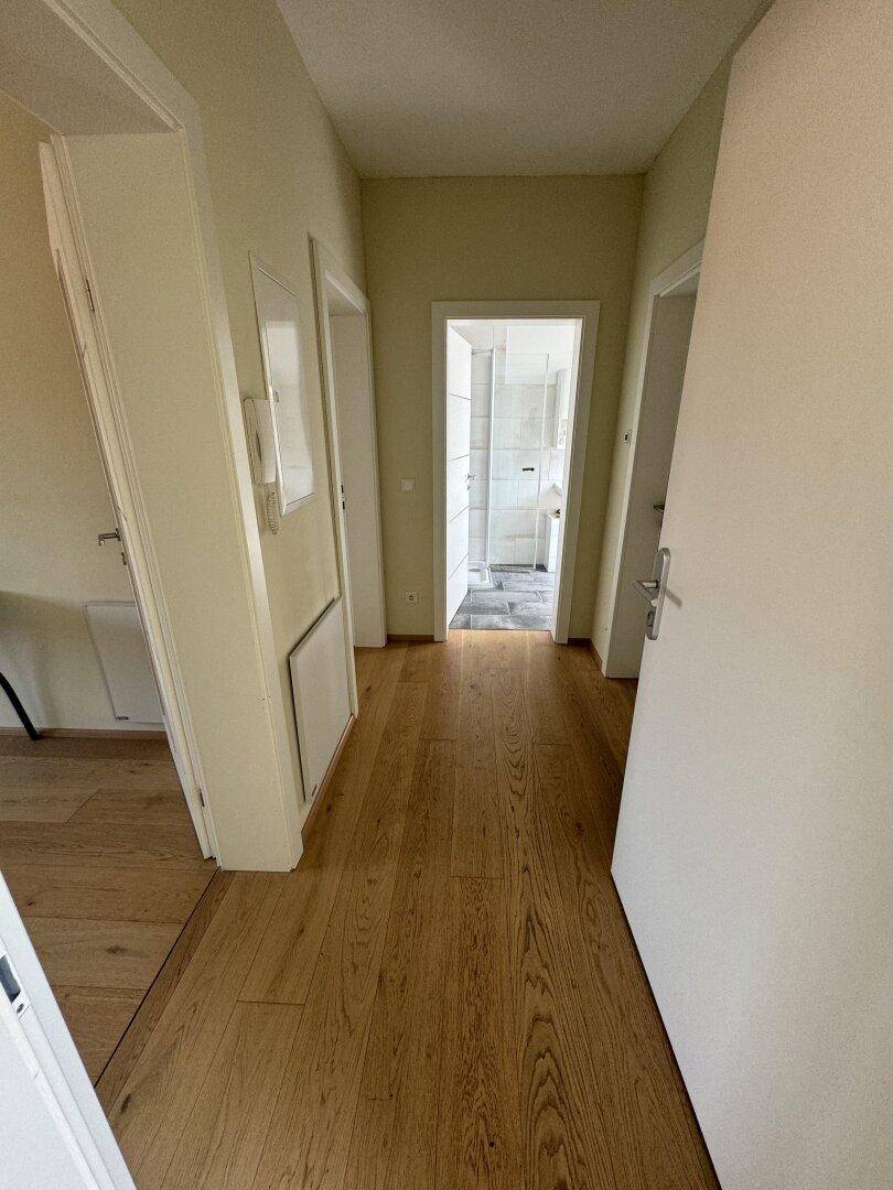 Heller Flur mit hellem Holzboden und weißen Türen, der zu verschiedenen Räumen führt.