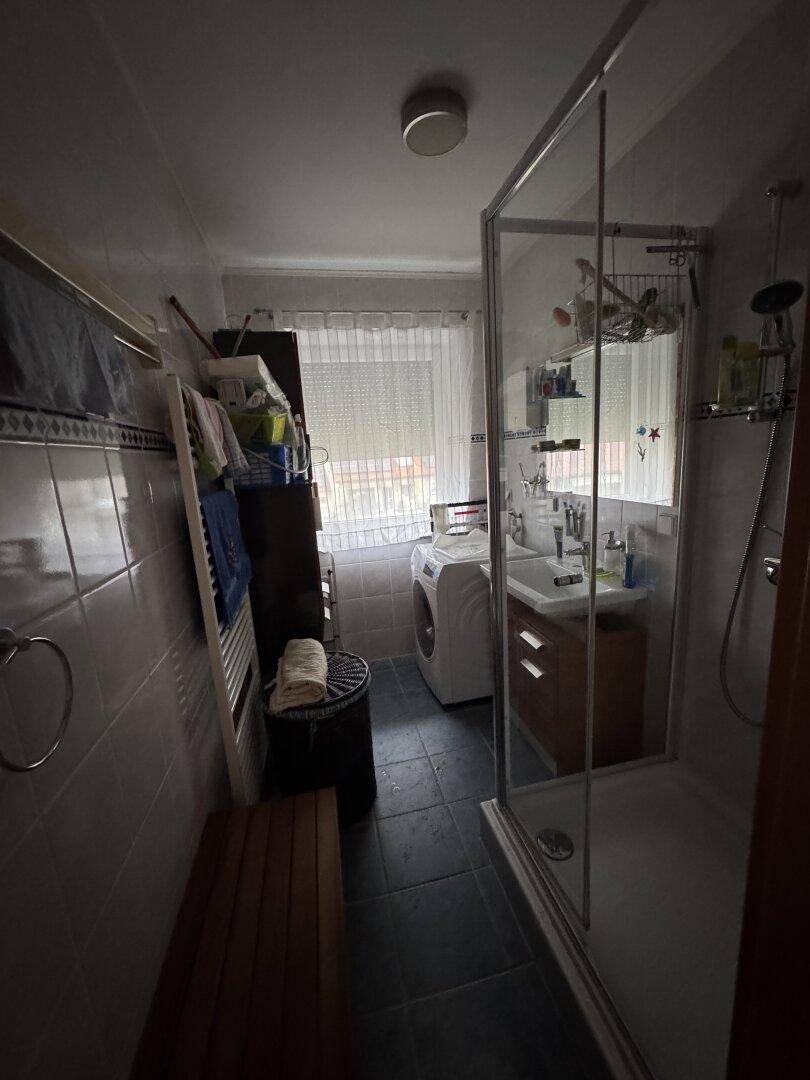 Badezimmer mit Duschkabine, Waschbecken, Waschmaschine und beheiztem Handtuchhalter.