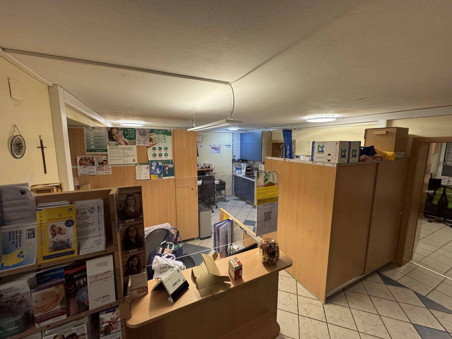 Großer Empfangs- und Bürobereich mit vielen Holzschränken und Fliesenboden.