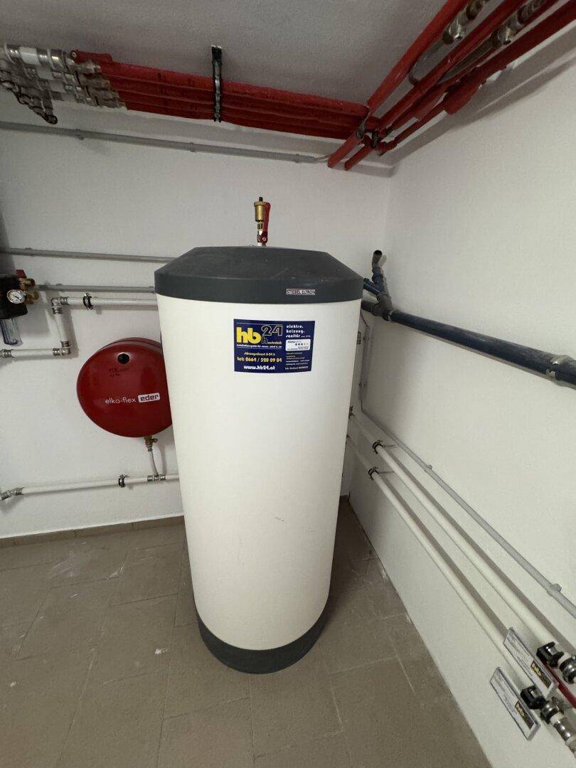 Hauswirtschaftsraum mit Warmwasserspeicher und sichtbaren Rohrleitungen.