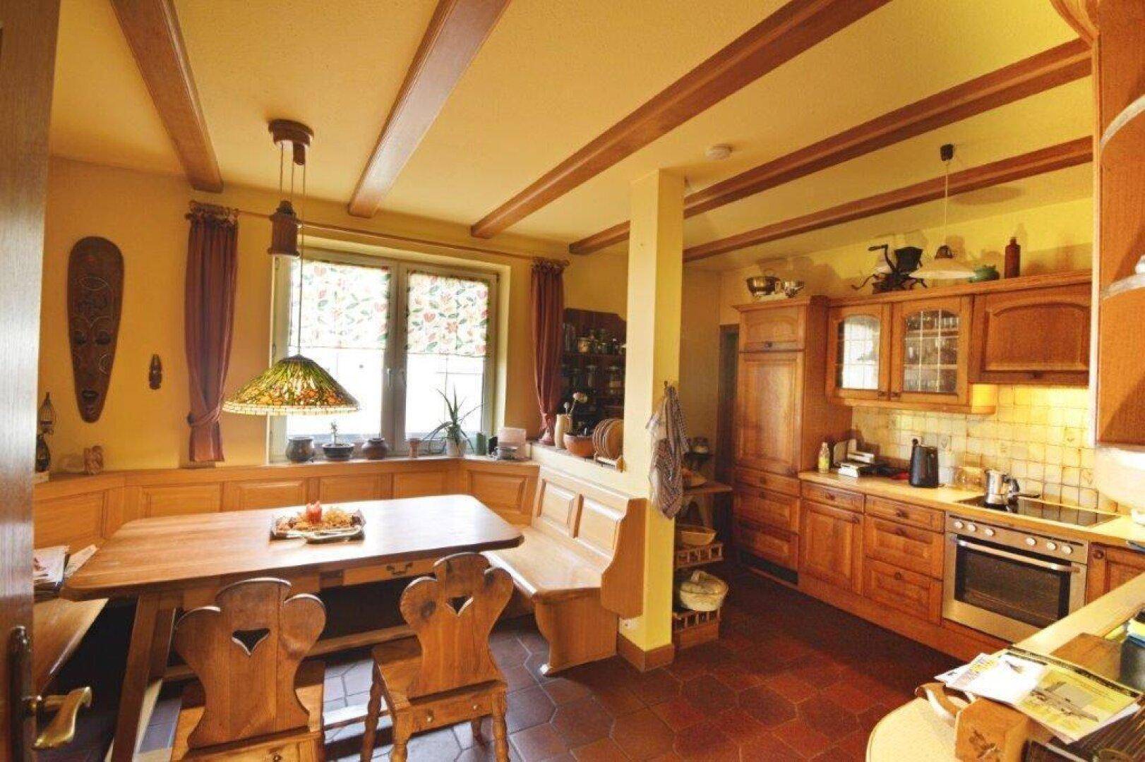 Gemütliche Wohnküche im Landhausstil mit Holzeinbauten und Essecke.