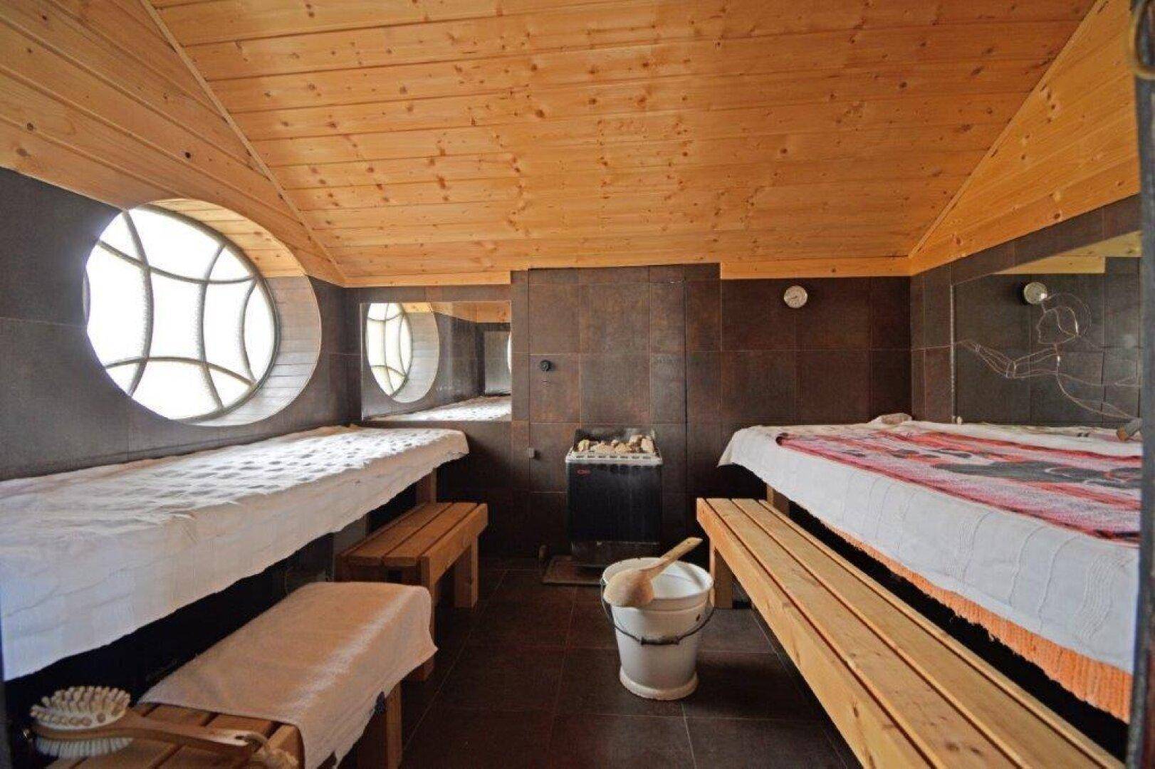 Wellnessbereich mit Holzverkleidung, runden Fenstern und Saunabänken.