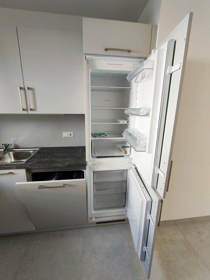 Integrierter Kühlschrank und Geschirrspüler in einer modernen Küche mit hellen Fronten.