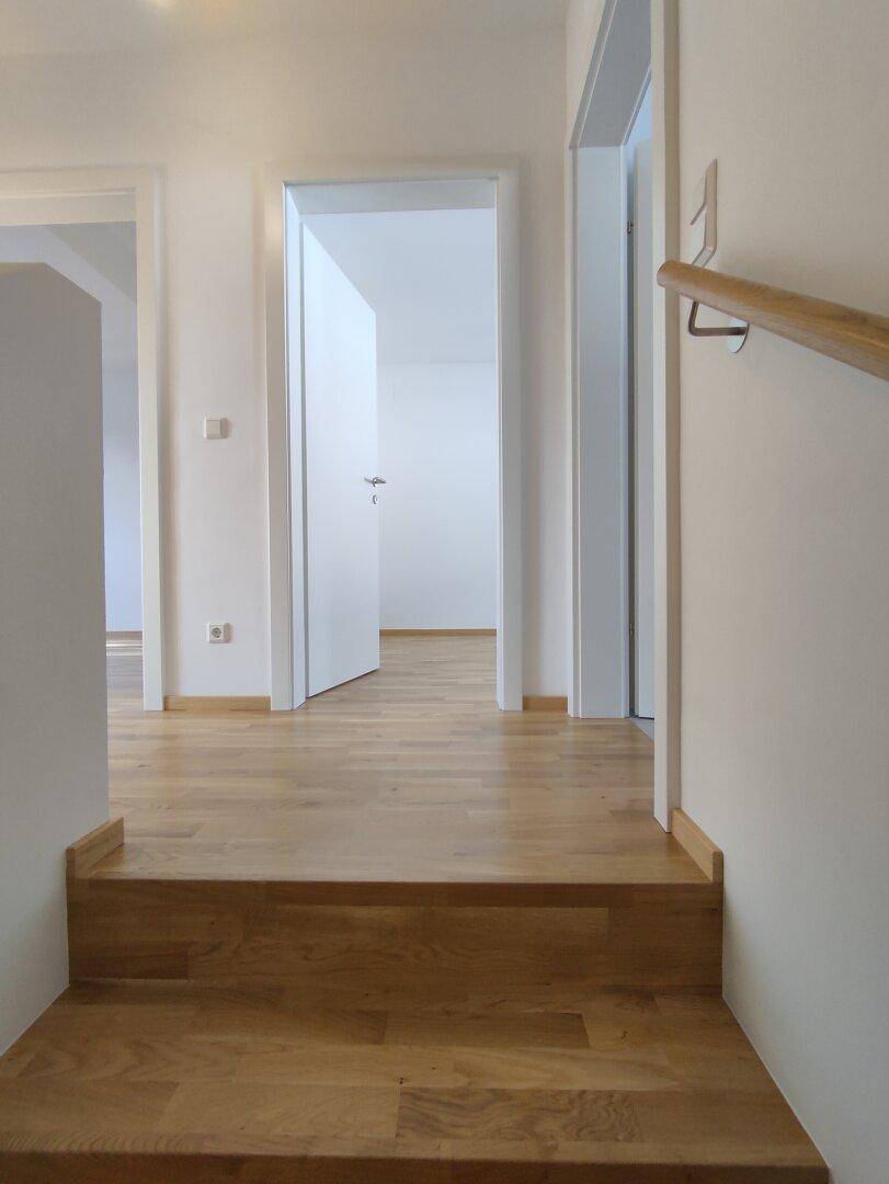 Heller Flur im Obergeschoss mit Holzfußboden und Zugang zu weiteren Zimmern.